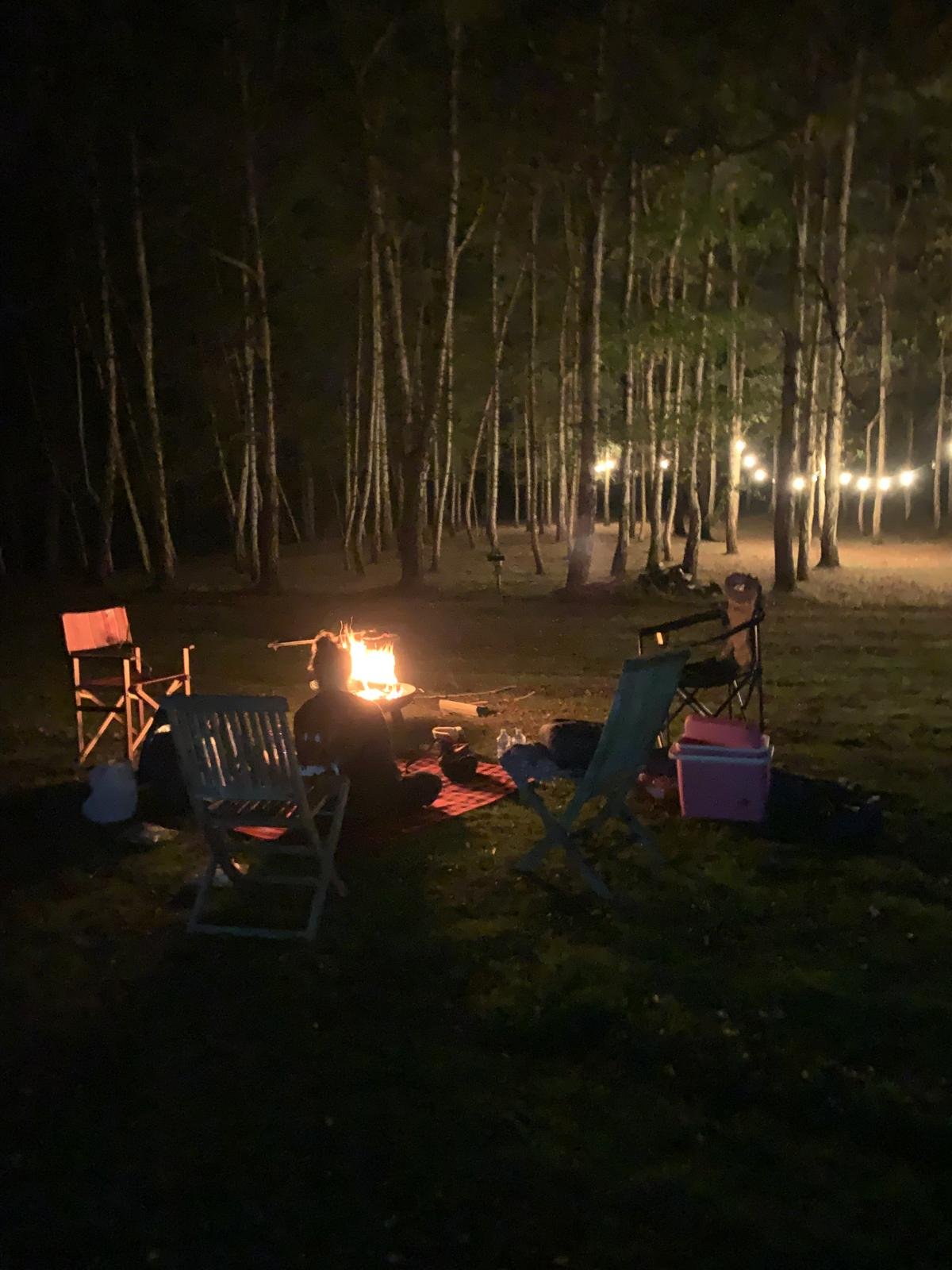 People sitting around a campfire at night learning outdoor cooking
