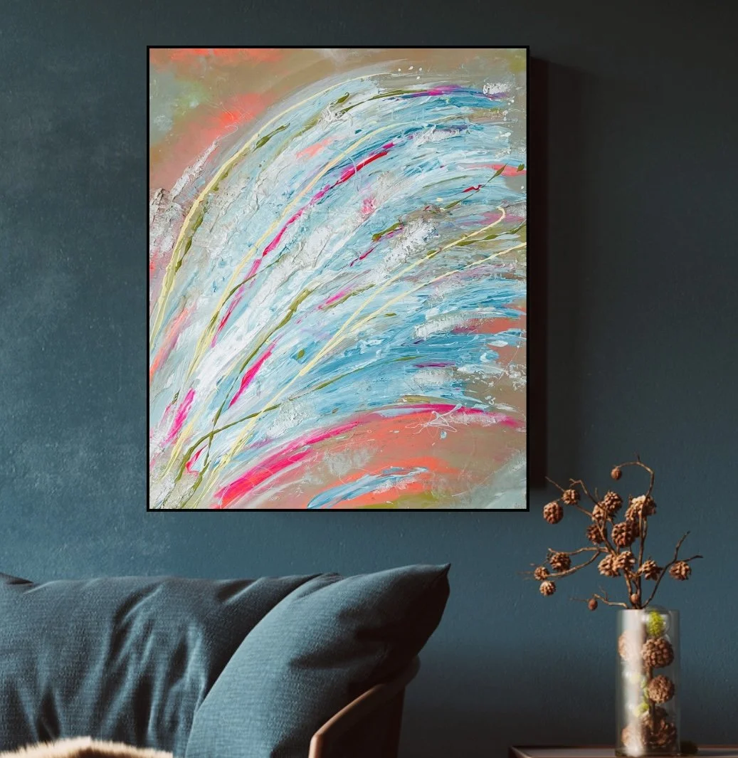 Peinture abstraite avec des coups de pinceau blancs, bleus, roses et verts sur un mur gris dans un salon contemporain.