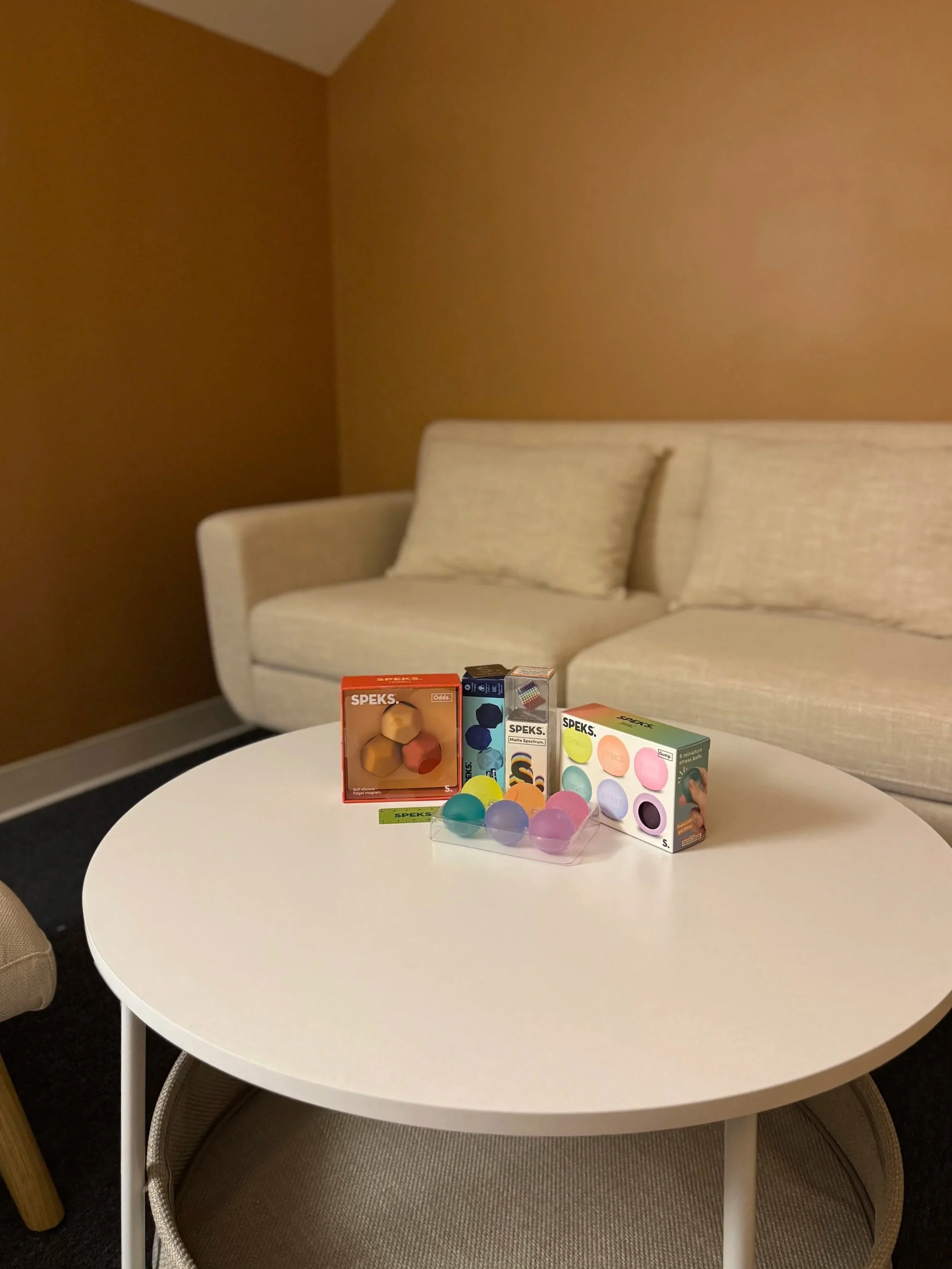 Couch in the office with a small table in front with various fidget toys displayed.