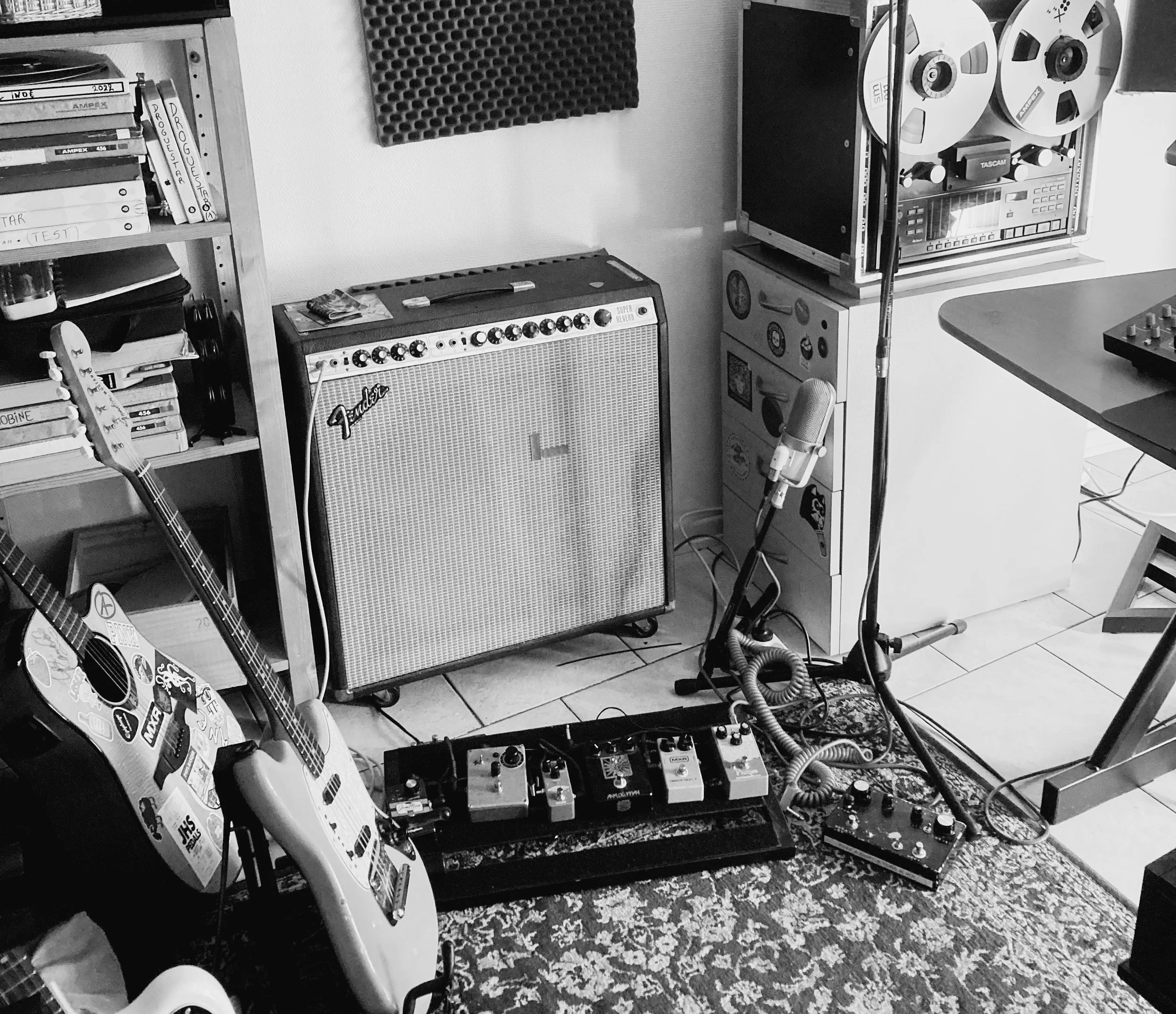 Studio de musique avec guitare électrique, amplificateur Fender, pédales d'effets, microphone, enregistrement et station de mixage.