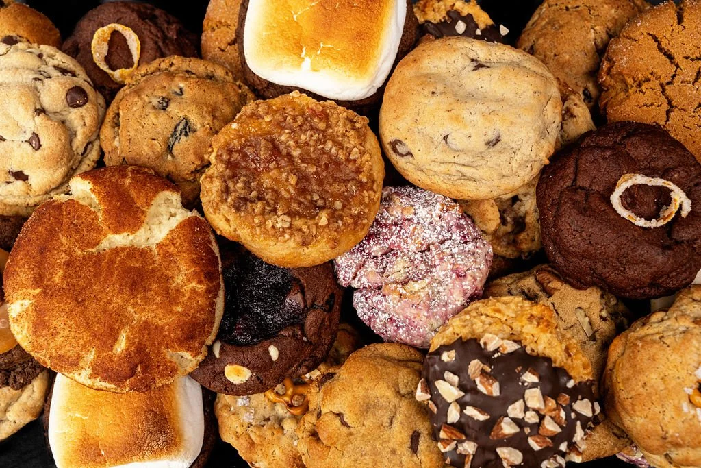 Assorted cookies including chocolate chip, oatmeal, and sugar cookies, with marshmallows, chocolate, and powdered sugar.