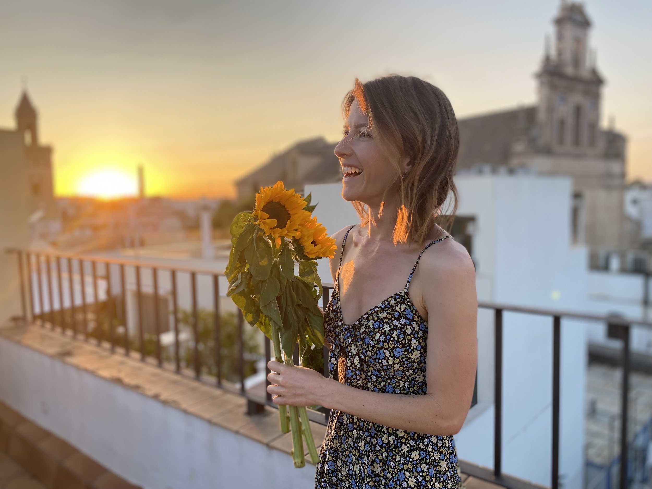 Woman holding sunflowers at sunset in a peaceful outdoor setting