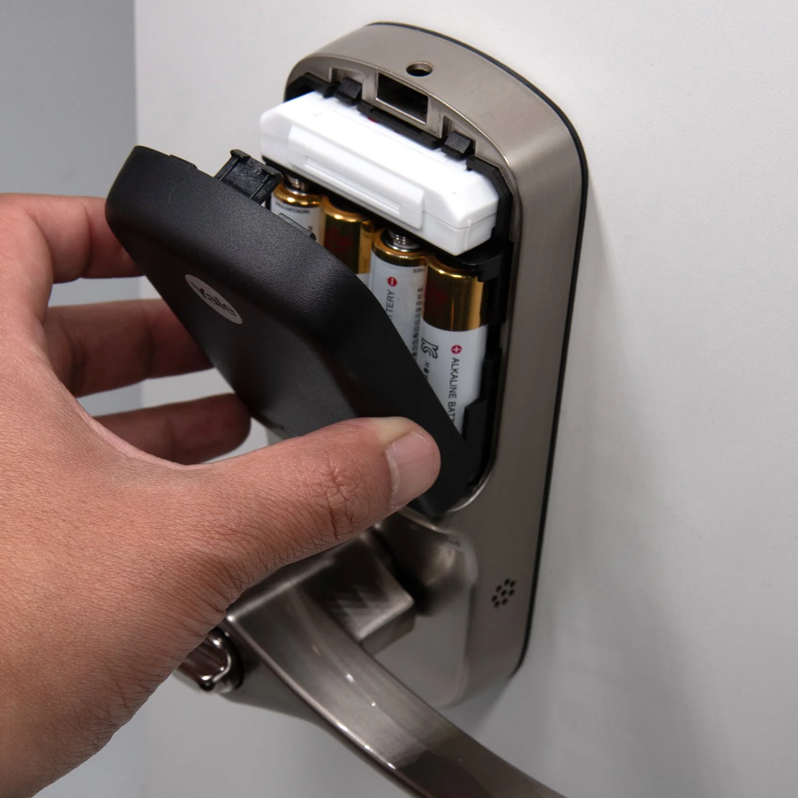 Person replacing batteries in a door lock mechanism.