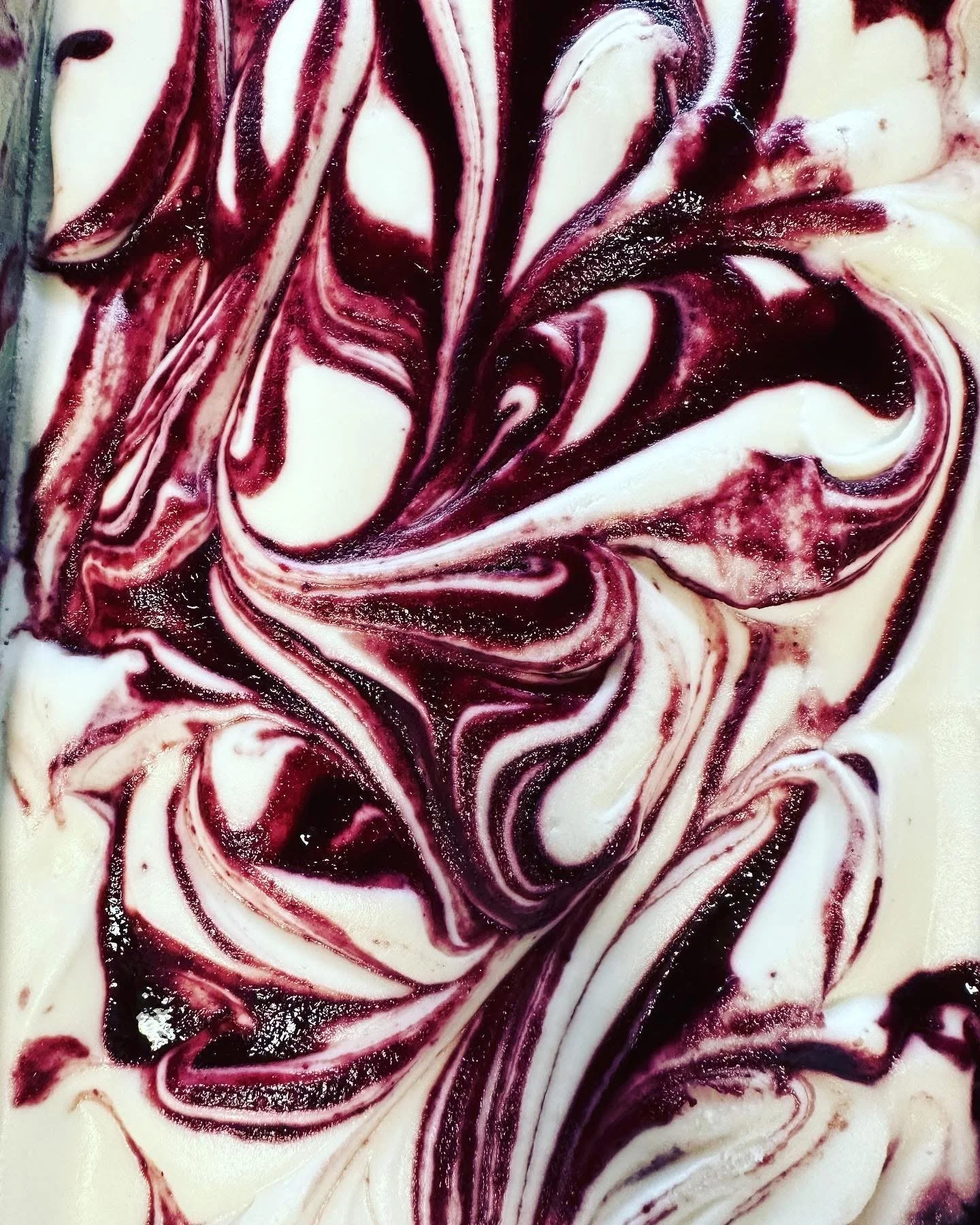 Close-up of a marble swirl pattern in a dessert, with red, purple, and white colors.