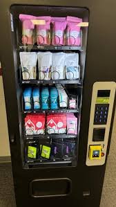 A vending machine with pink, white, blue, and red packets of snacks or candies, a keypad, and a payment terminal.