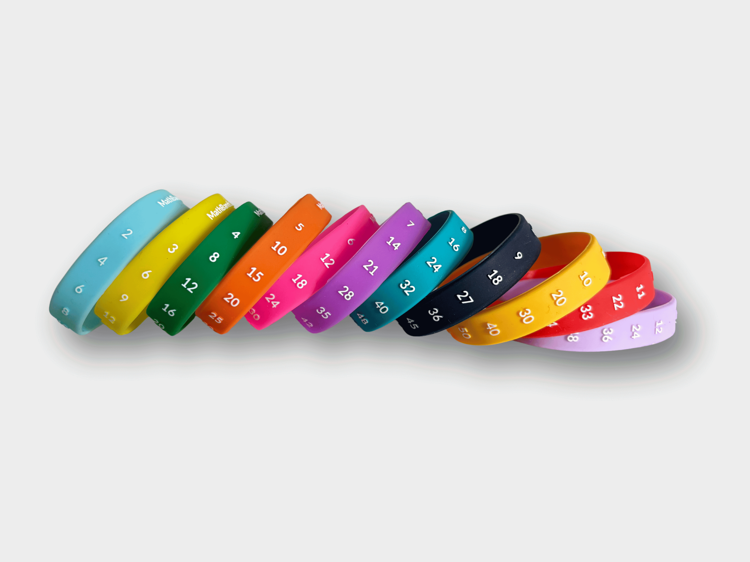 Colorful silicone bracelets with engraved numbers and multiplication patterns, arranged in a curved line on a light background.