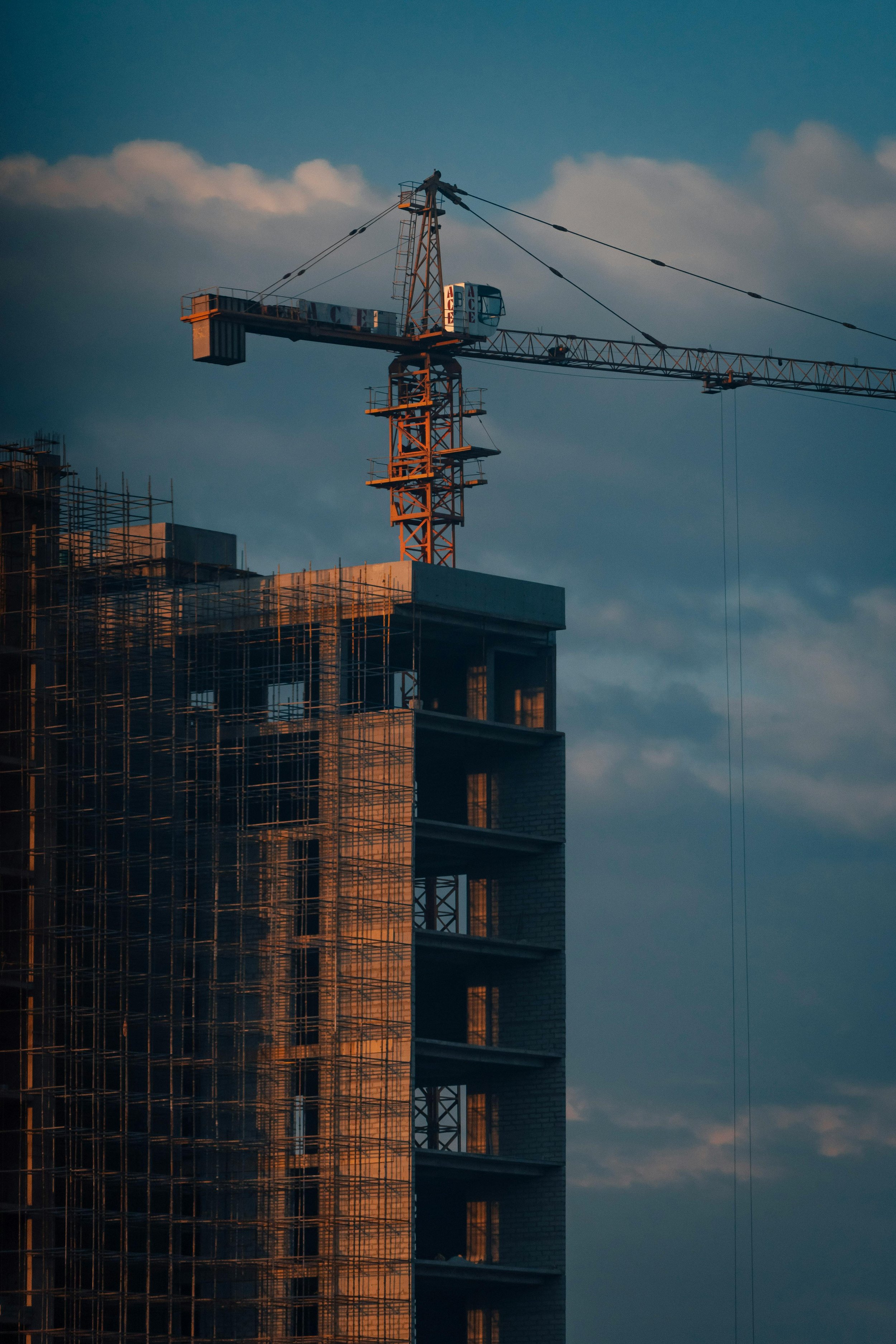 Construction crane on a tall building under construction during sunset.