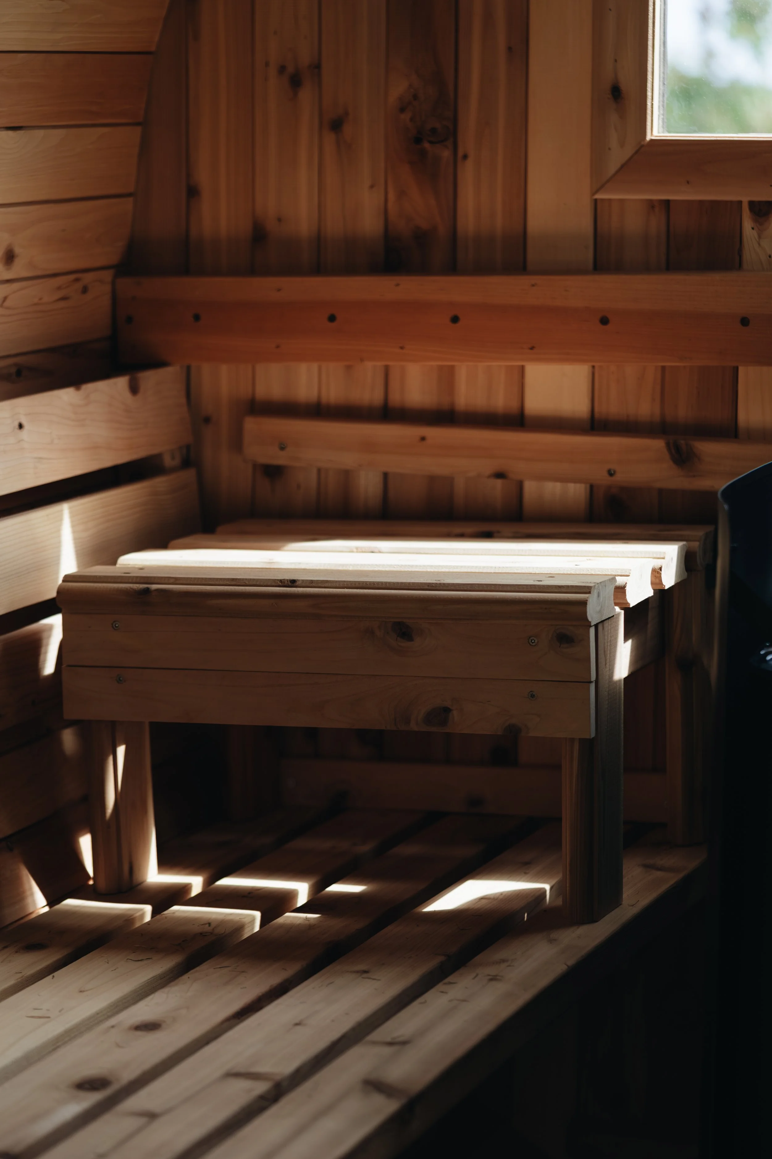 Wooden interior with slatted ceiling and a small square window letting in natural light.