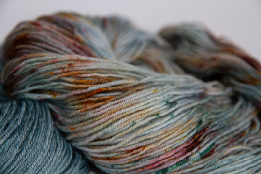 Close-up of a variegated hand-dyed skein of yarn with shades of blue, orange, red, and green.