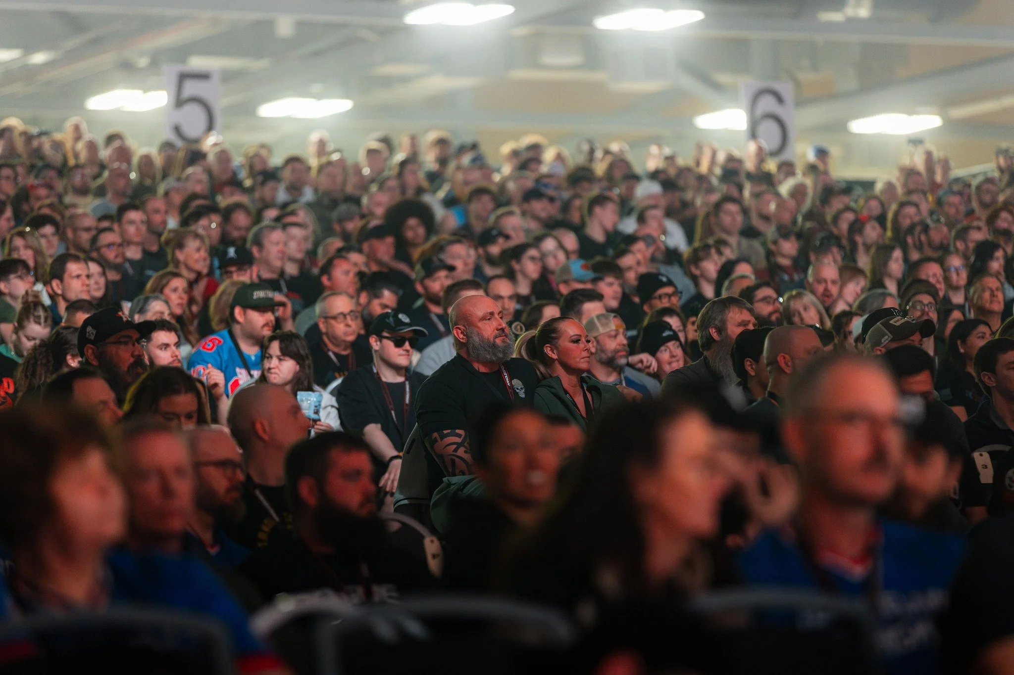 A large audience seated at an indoor event, attentively watching a presentation or performance.
