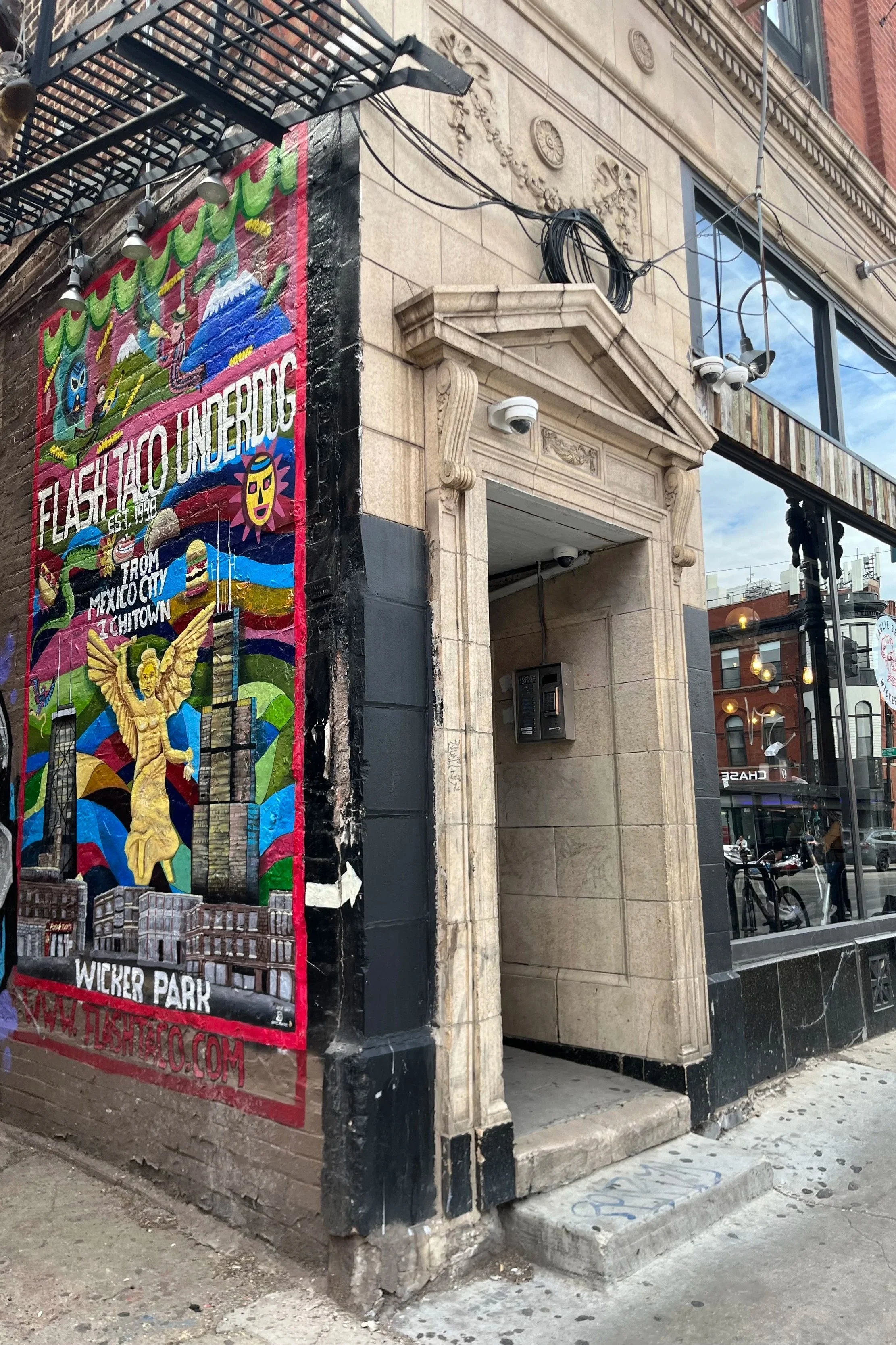 The entry door for 1564 N Damen Avenue is just past the alley with its bright Flash Taco mural.