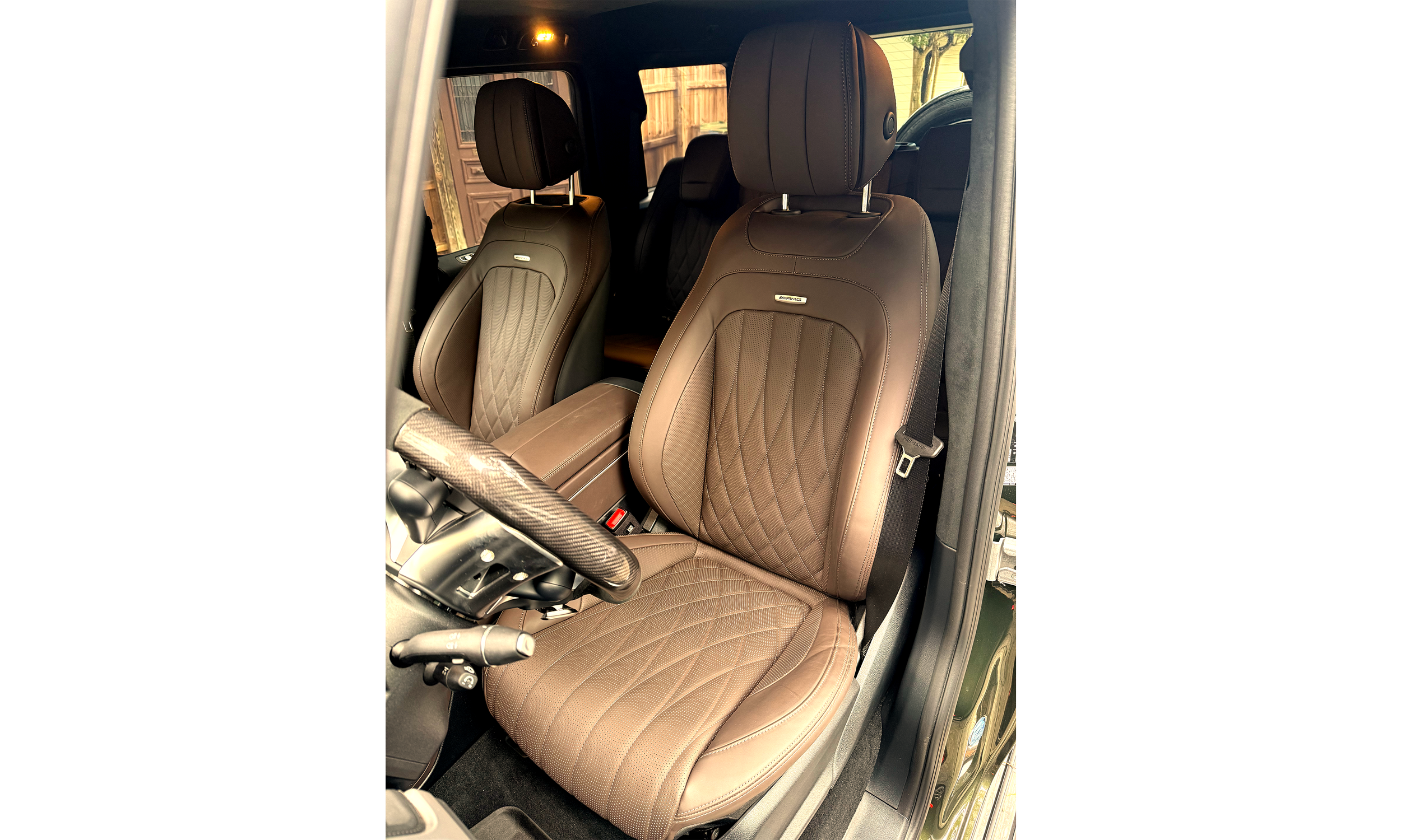 Interior of a 2025 Mercedes-Benz G63 vehicle showing two espresso brown leather front seats with diamond stitching and headrests, with a steering wheel partially visible on the left.