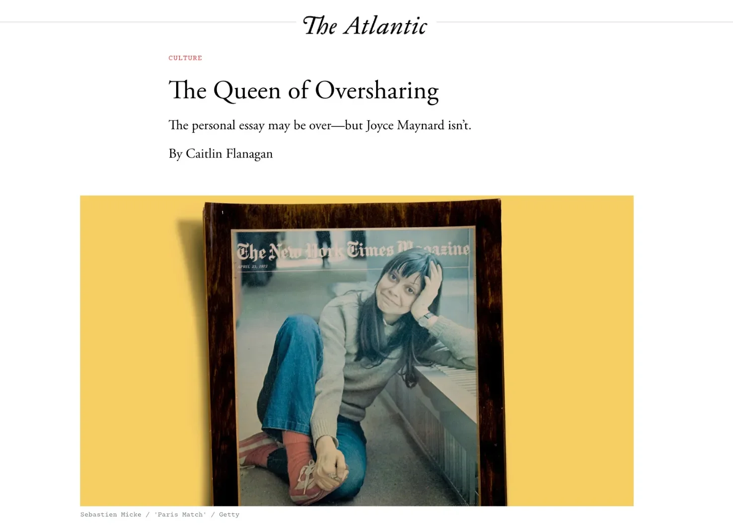 A magazine page featuring an article titled 'The Queen of Oversharing' with a photograph of a young woman sitting inside The New York Times Magazine in front of a yellow background. The woman is sitting on the floor, leaning on a bench, with her head resting on her hand, wearing a grey sweater, blue jeans, and pink socks, with dark hair and a slight smile.
