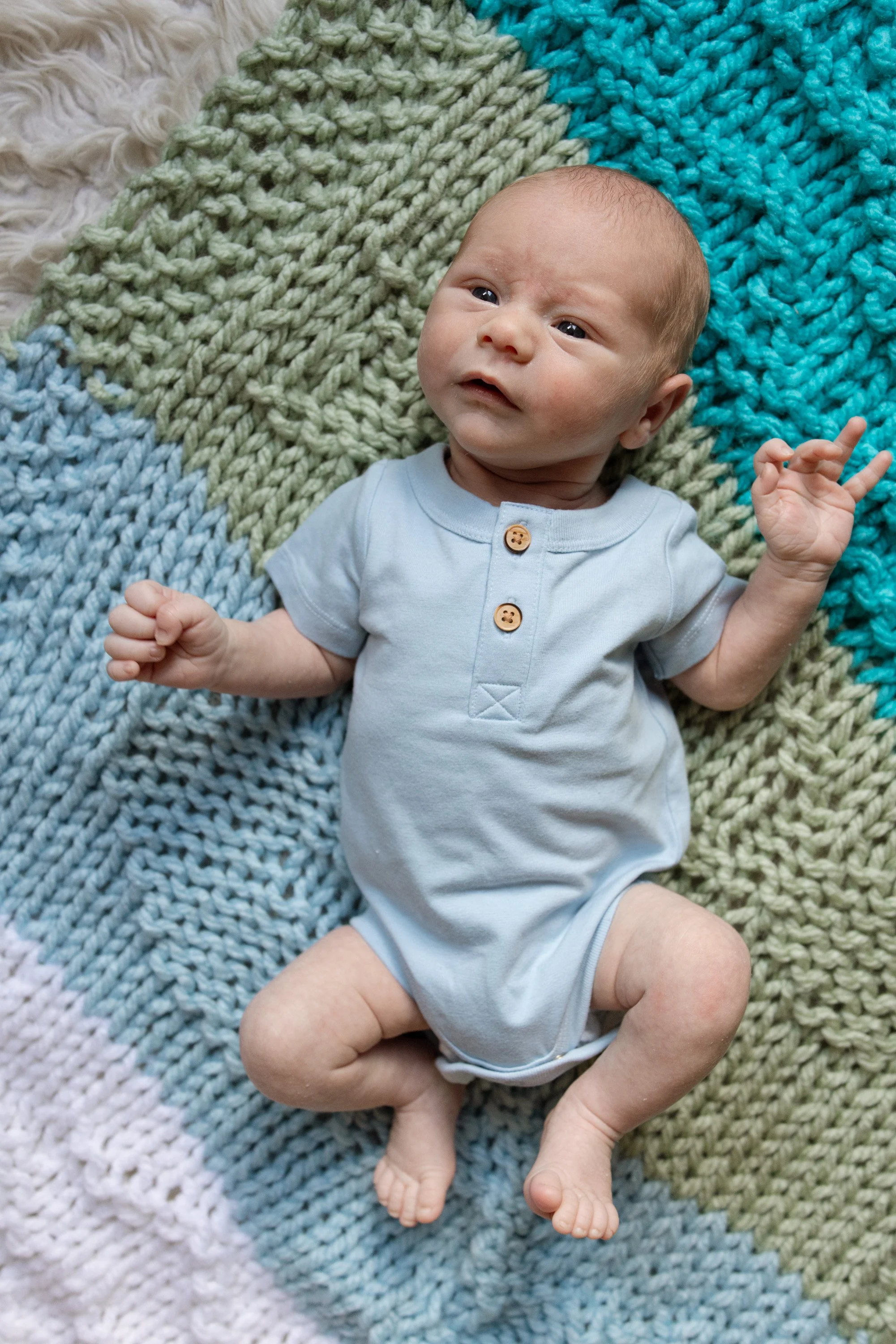 newborn baby boy laying on a hand knitted blanket, photo captured by Austin in home newborn photographer Hailey Copland 