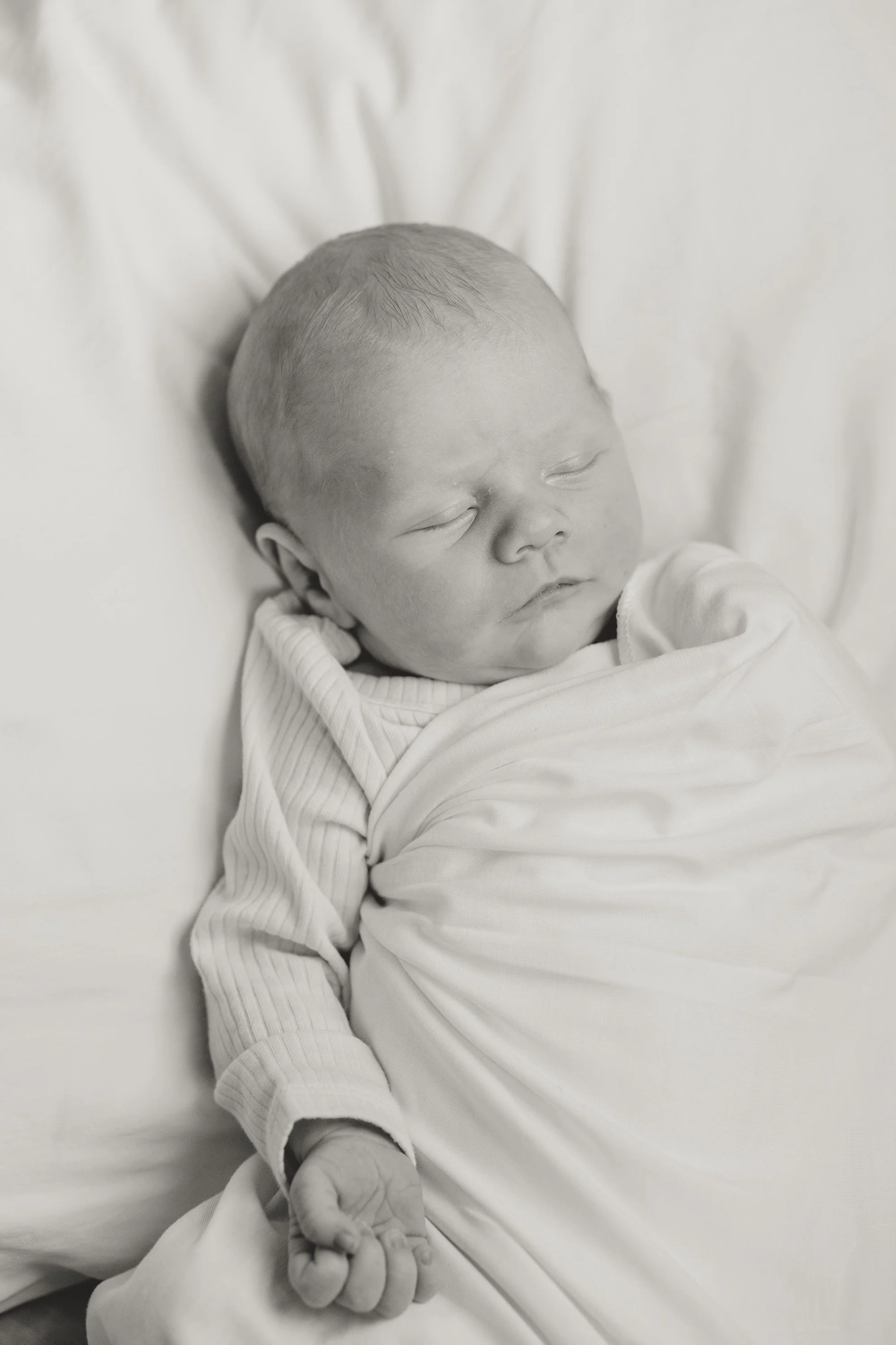 in-home newborn photo of baby boy swaddled and laying on bed, photo captured by Austin in home newborn photographer Hailey Copland 