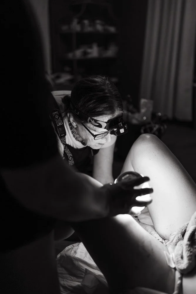 A woman wearing a headlamp is practicing on a sculpture in a studio, with a person nearby observing.