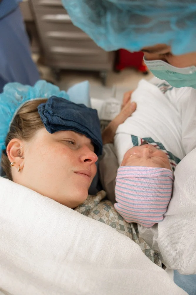 New mother and father holding their newborn in hospital, with the mother lying in bed and the father at her side, both looking lovingly at the baby.