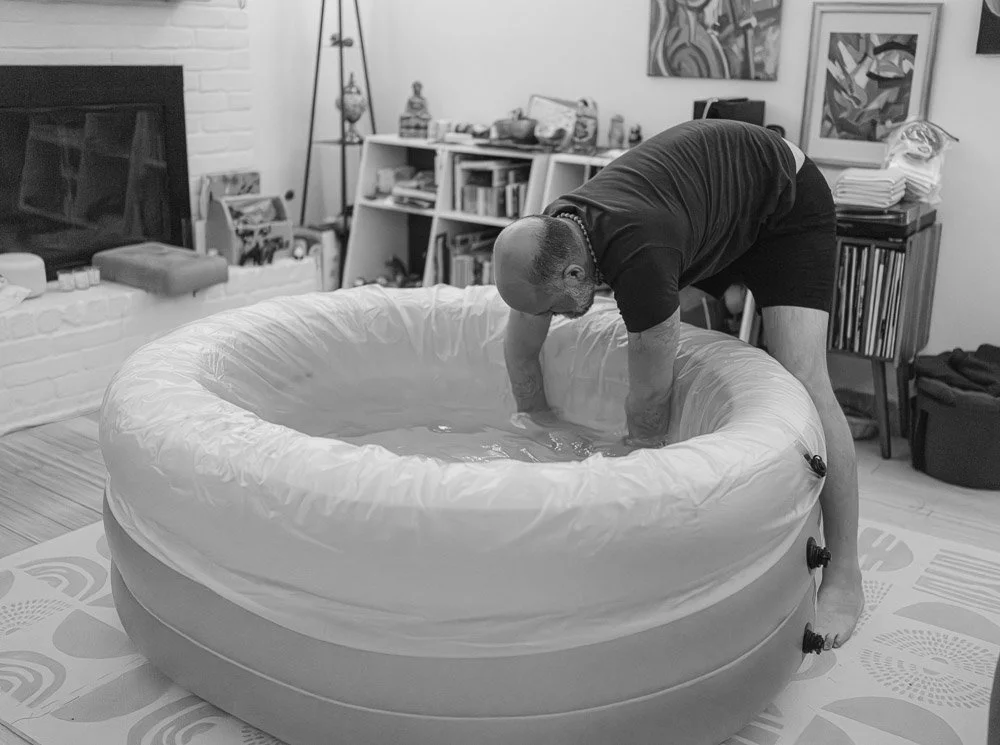 A man is setting up an inflatable hot tub indoors in a living room.