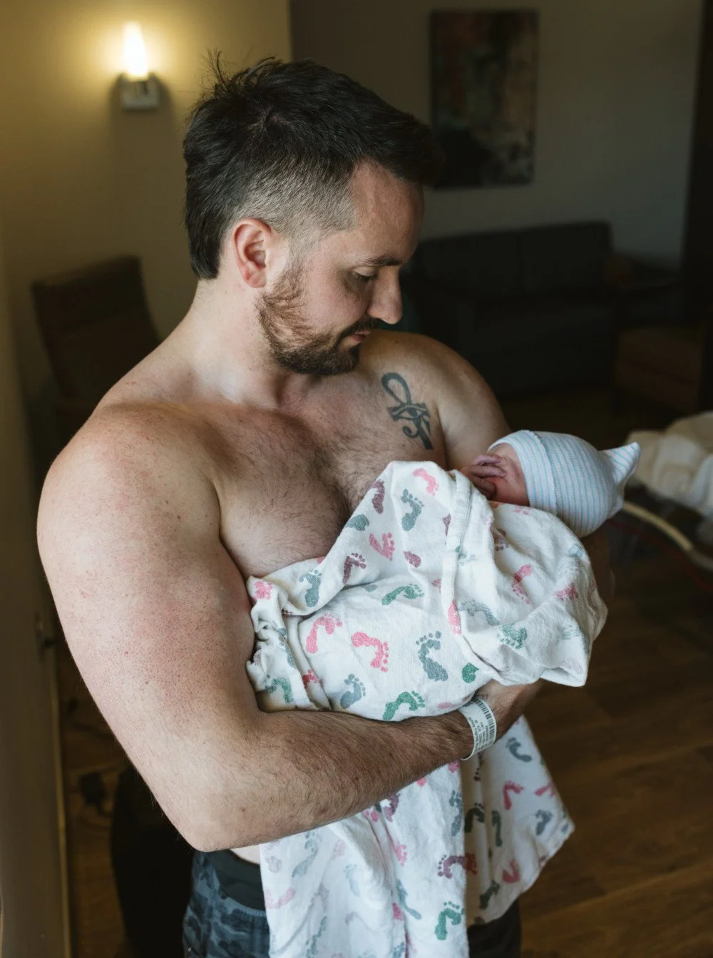 A man holding a newborn baby in a hospital room.