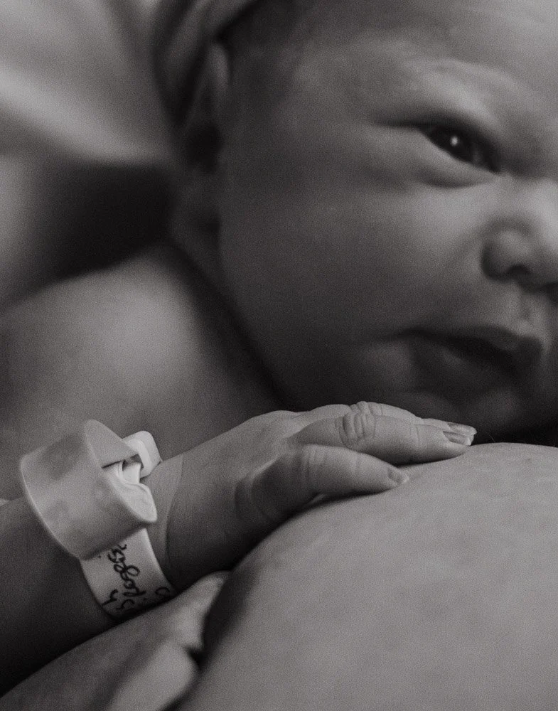 Close-up of a sleeping baby with a hospital wristband, lying on a pillow.