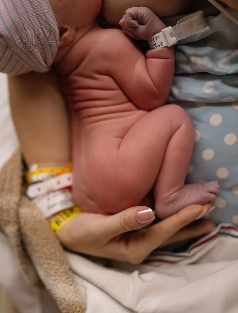 Austin birth photograph of mom's arm cradling a naked newborn baby with a lot of wrinkles in the hospital