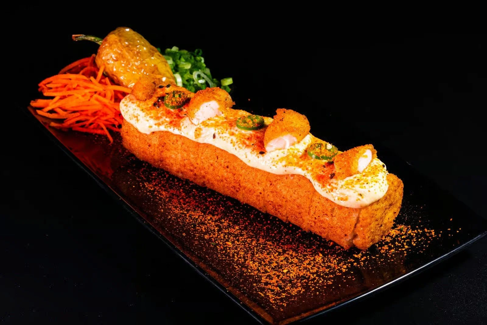 Fried fish fillet topped with creamy sauce, sliced jalapenos, and spices served with shredded carrots, chopped green onions, and a wedge of lime.