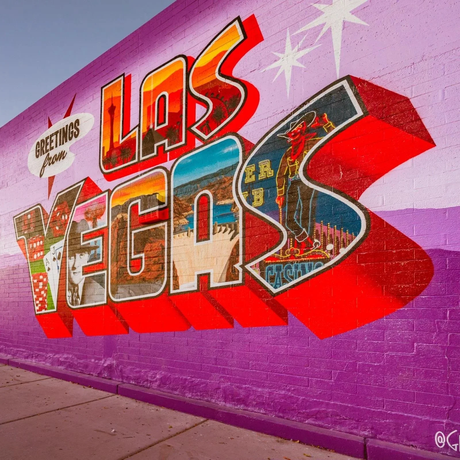 Colorful mural on a purple wall saying 'Greetings from Las Vegas' with images of the Las Vegas Strip, a casino sign, a woman, and playing cards.