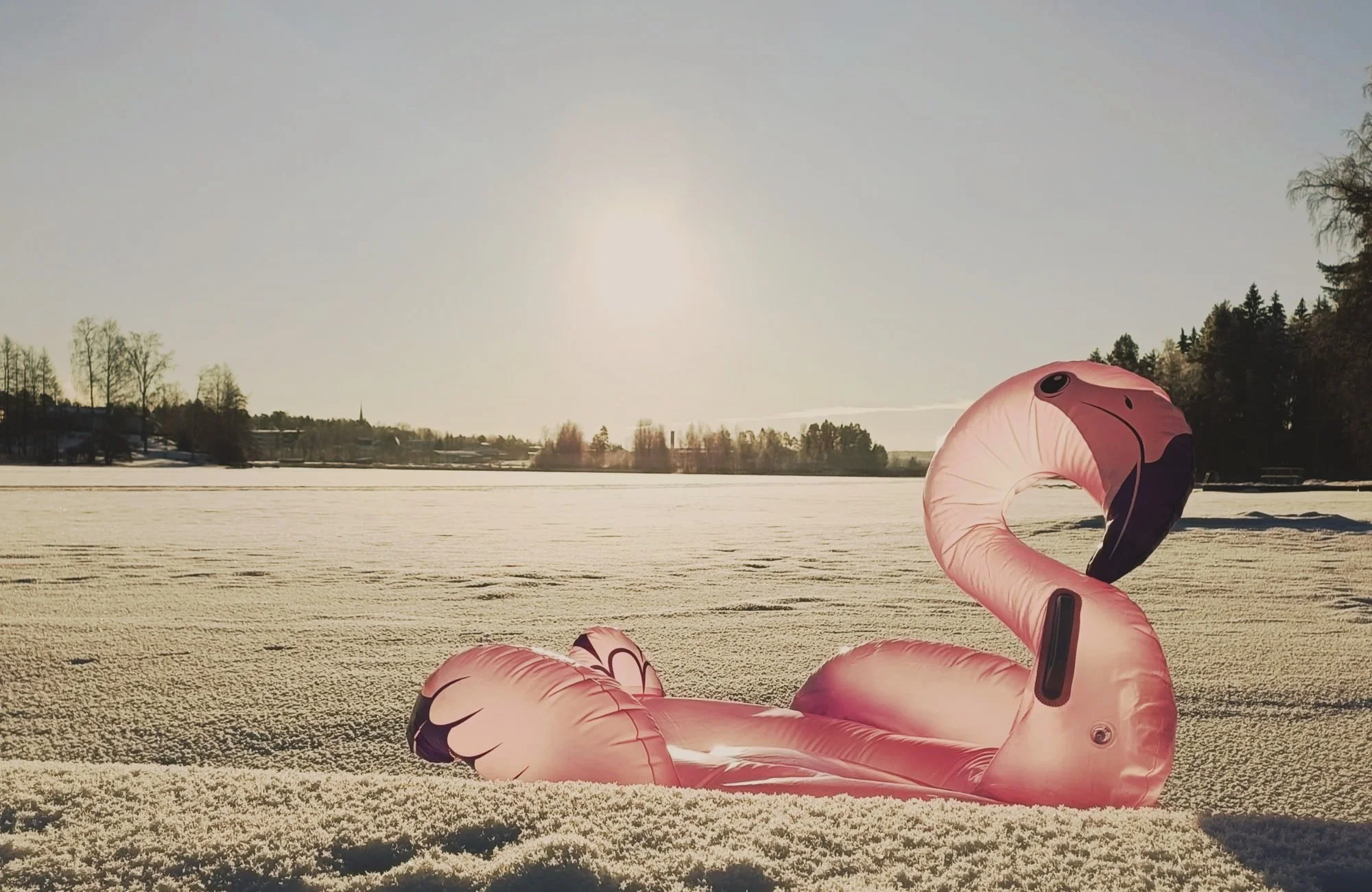 Pinkki flamingo-uimarengas jäisellä ja lumisella järvellä kuvastamassa kevätväsymystä, ylivireyttä ja ADHD-oivalluksia hyvinvointiblogissa.