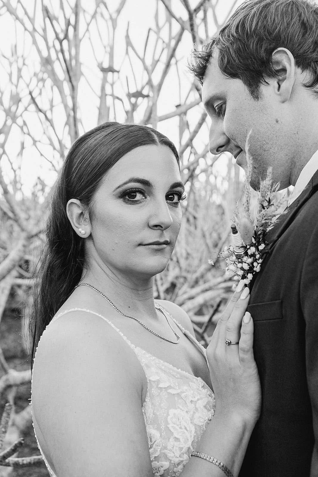 Black and white photo of a woman and man in wedding attire, close-up outdoor portrait.