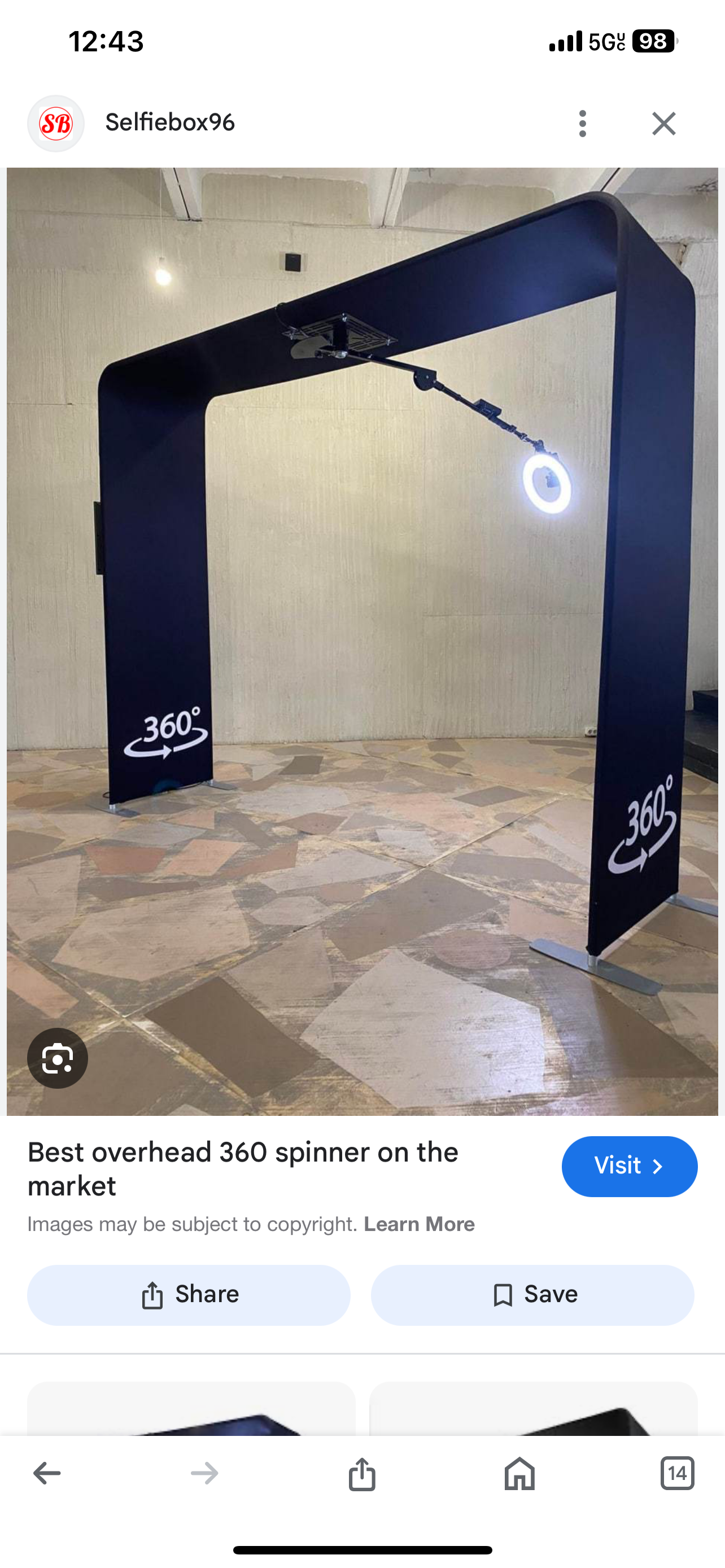 A circular overhead 360-degree spinning photo booth with black frame and illuminated ring light in a room with tiled floor and light-colored walls.