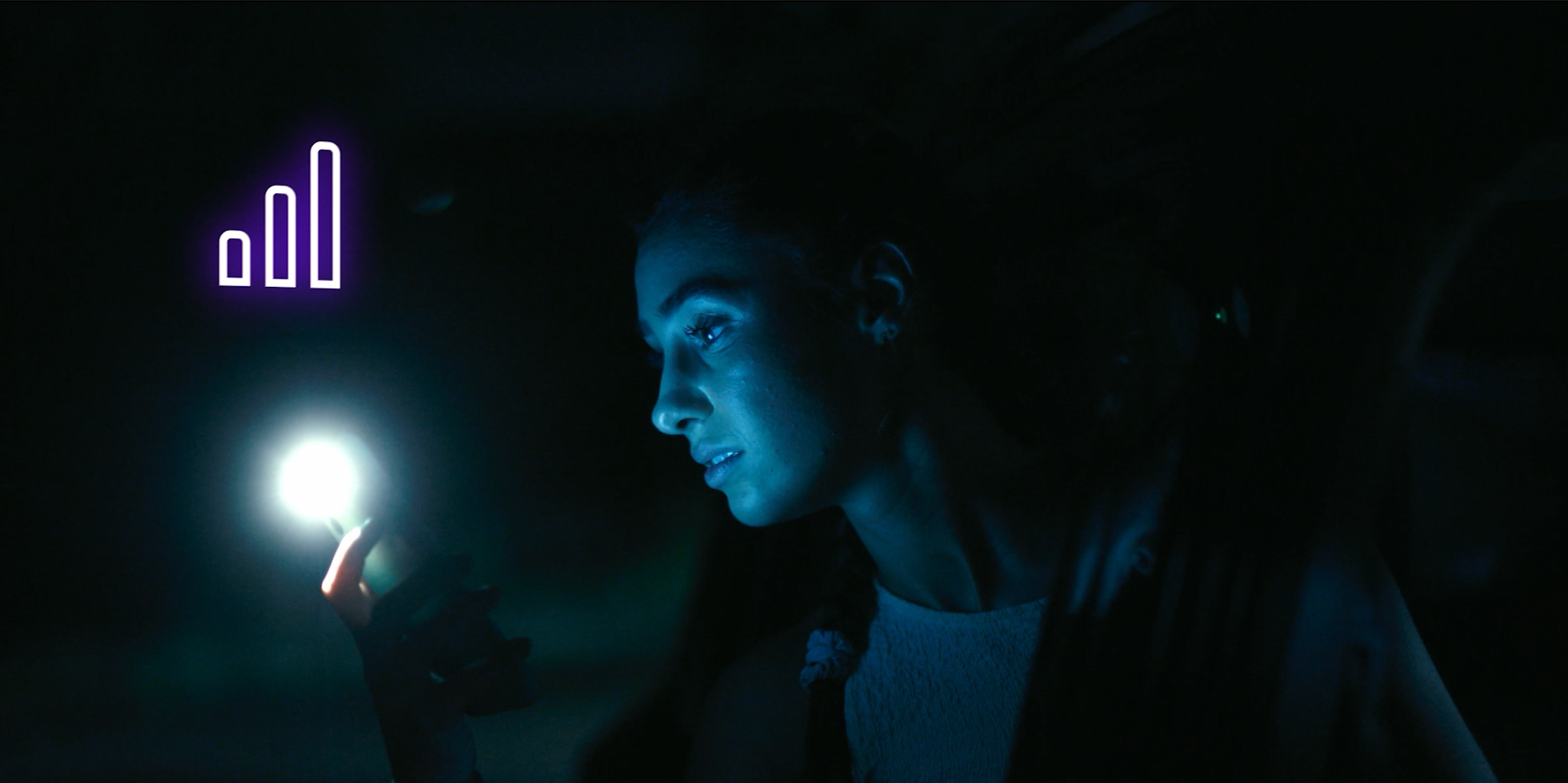 Young woman in dark setting illuminated by a phone's bright screen, with a glowing purple signal icon graphic in the background.