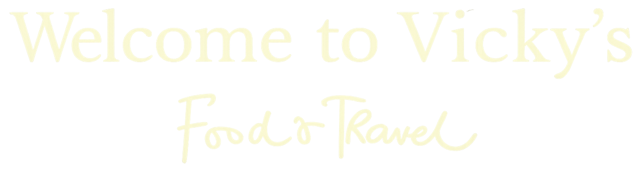 Sign that reads "Welcome to Vicky's Food & Travel" in script and serif fonts.