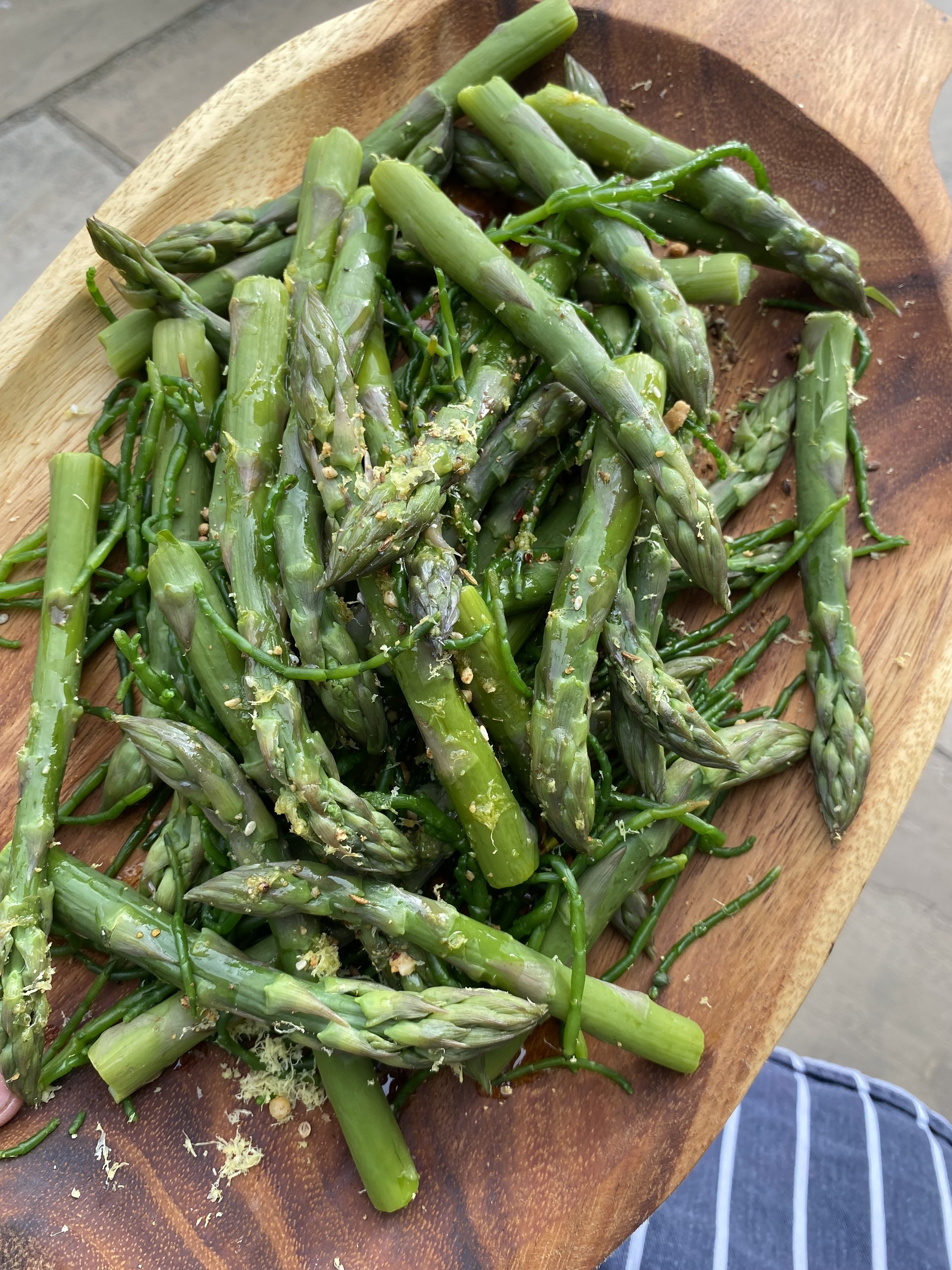 Fresh chopped asparagus salad with herbs on a wooden bowl.