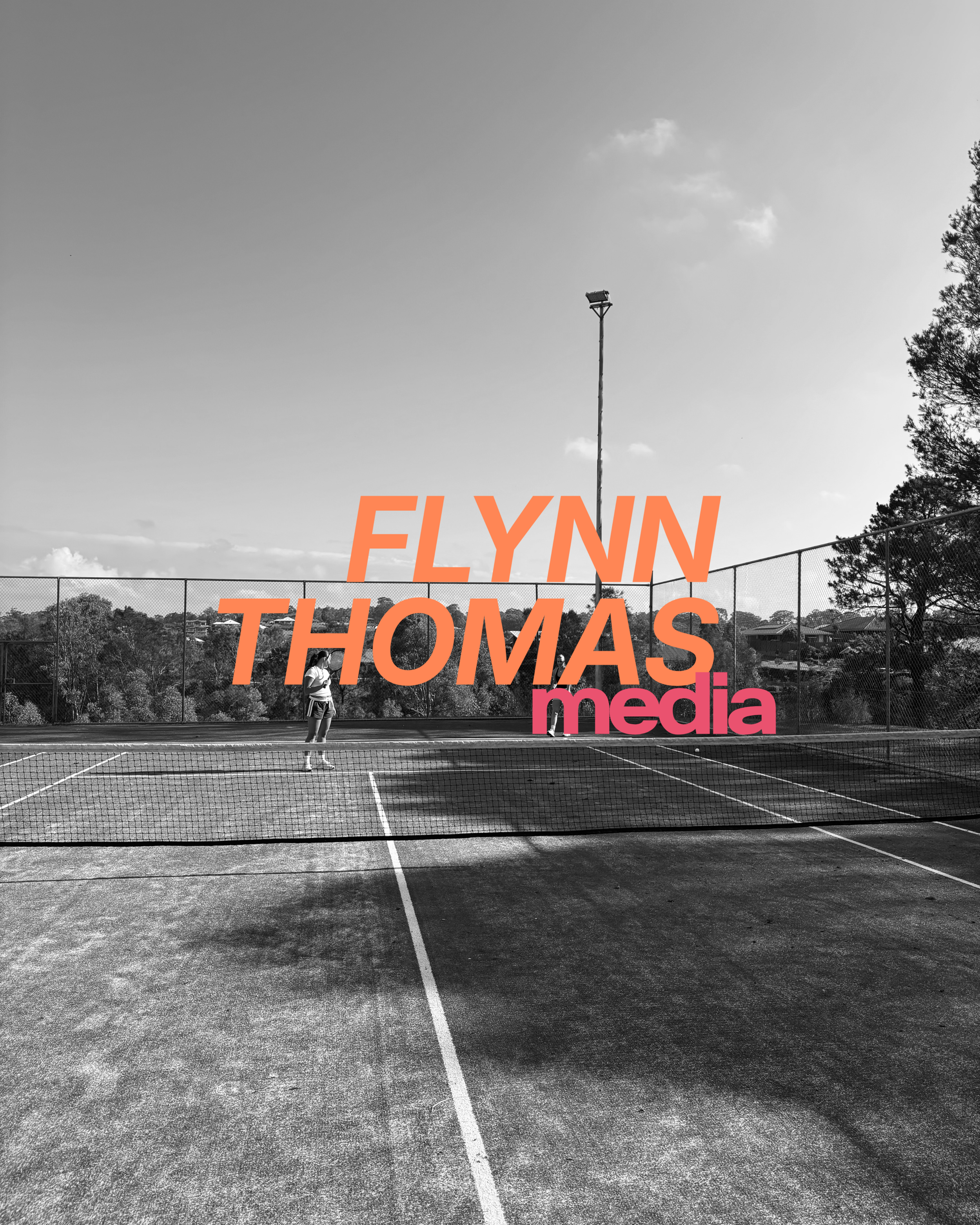 Black and white photo of a tennis court with a person standing near the net, and text overlay reading 'FLYNN THOMAS media' in orange and pink.