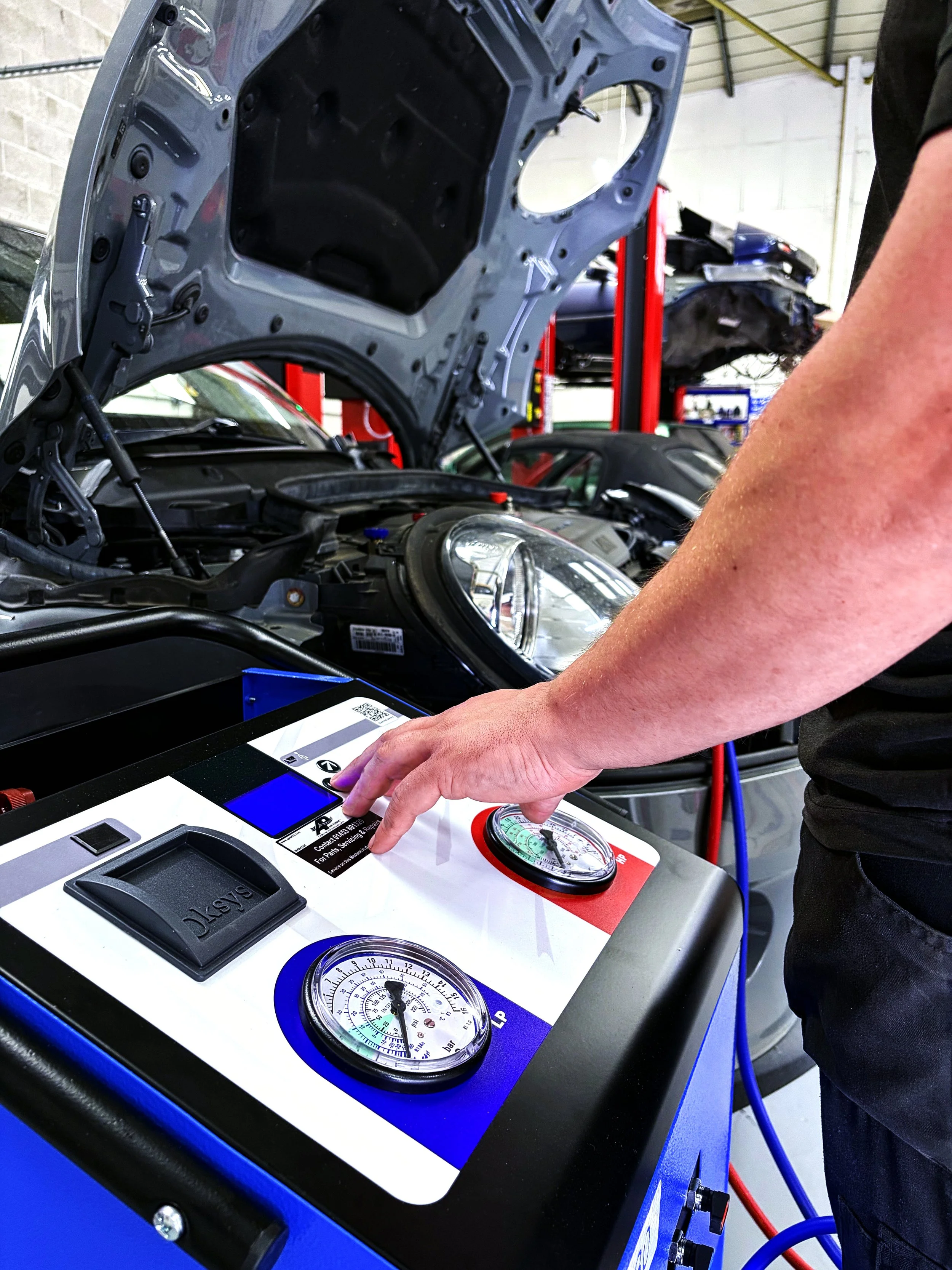 A mechanic working on a car engine using a diagnostic machine in an auto repair shop.
