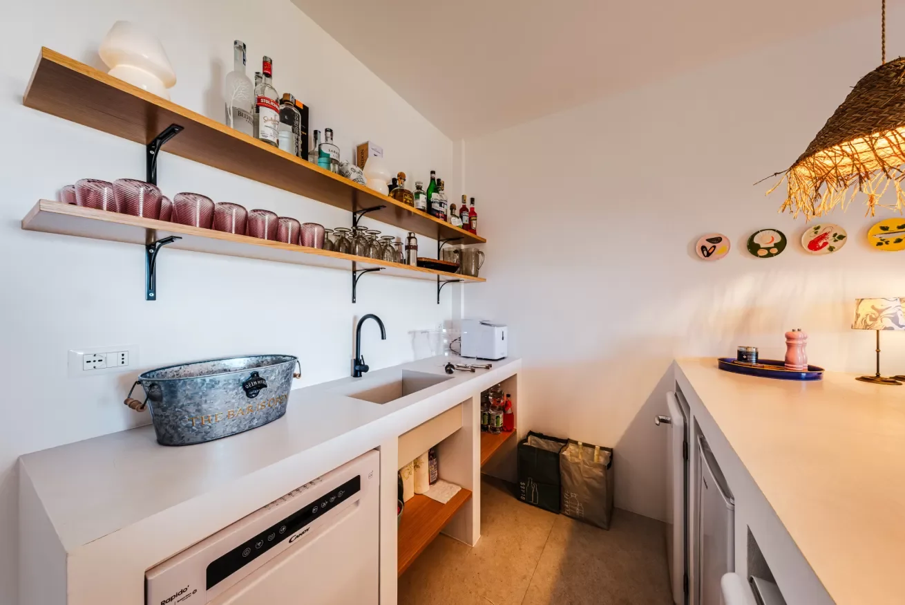 Small kitchen with open shelving, a white countertop with a sink, and decorative plates on the wall.