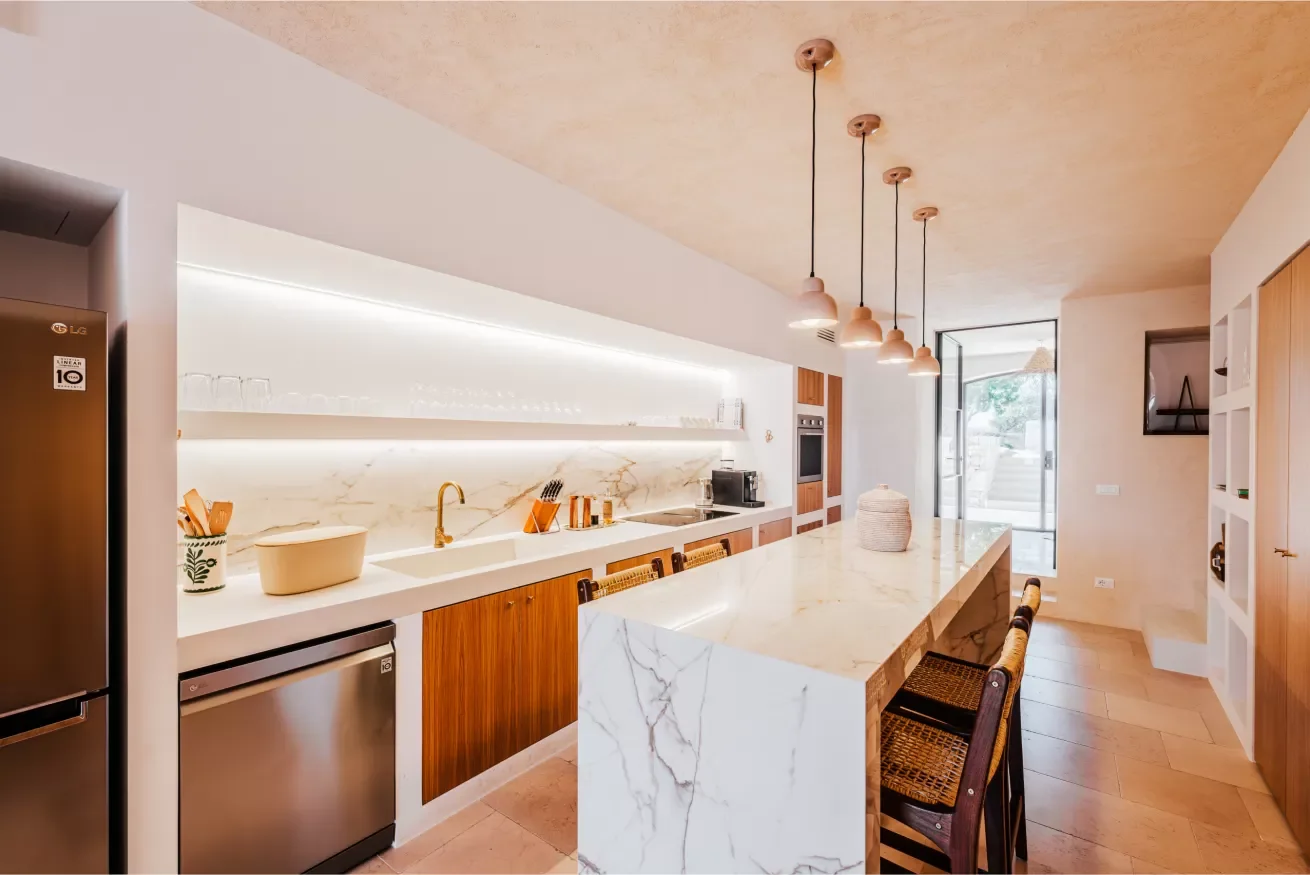 Modern kitchen with marble island, pendant lighting, and wooden cabinets.