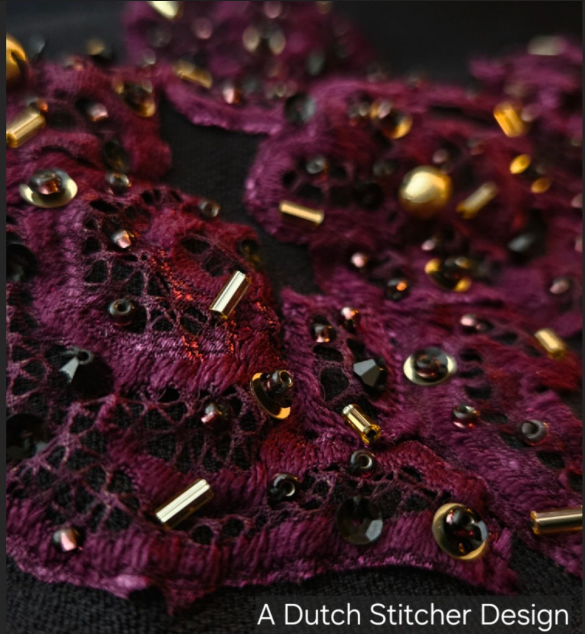 Close-up of deep red Bordeaux lace fabric adorned with black and gold beads and sequins, embroidered by AcDutch Stitcher Design.