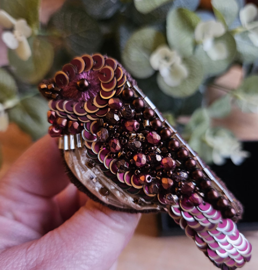 Decorative brooch adorned with purple and pink sequins and beads.