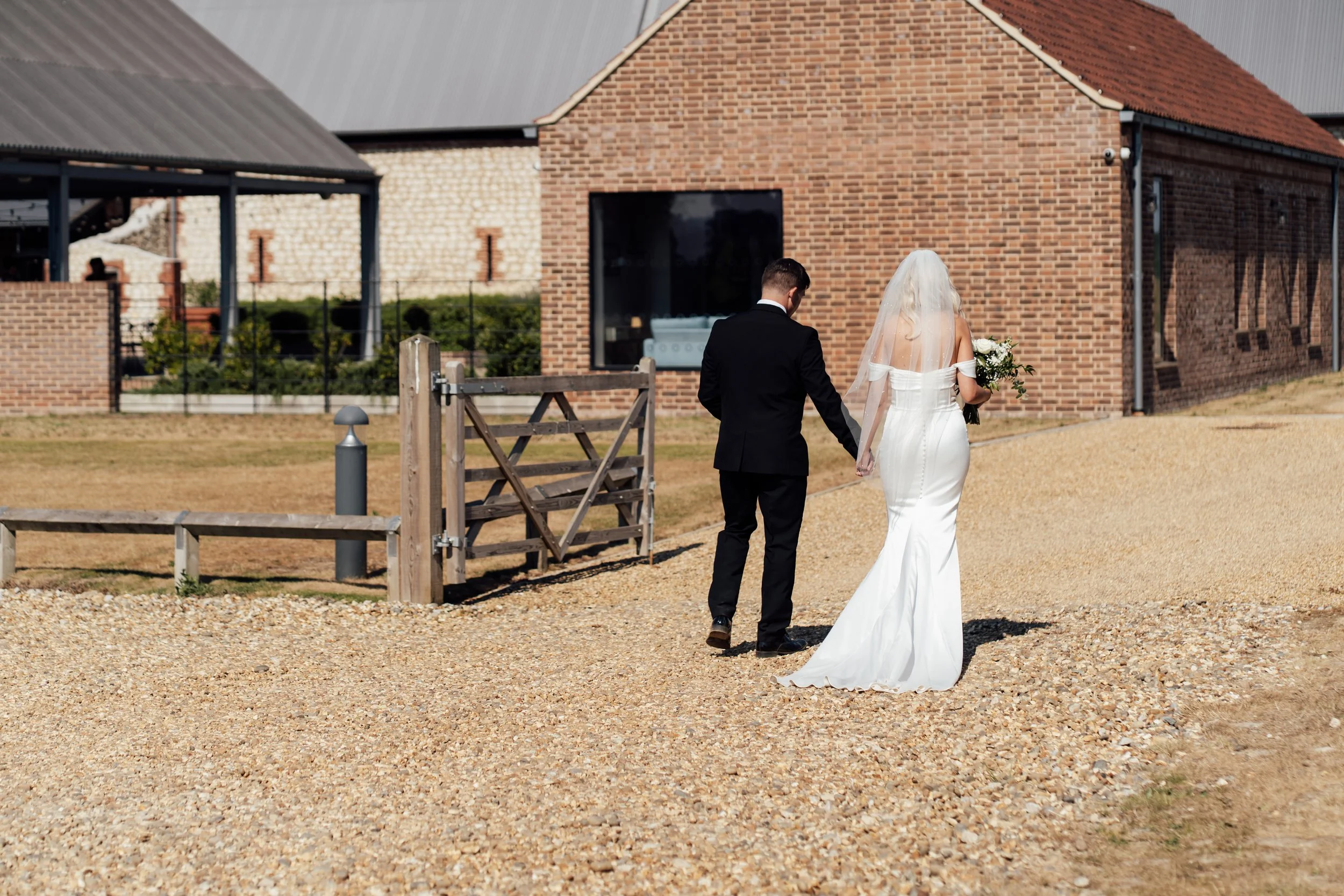 Bride and groom walking hand in hand during their relaxed wedding day portraits at Abbey Barns Norfolk 