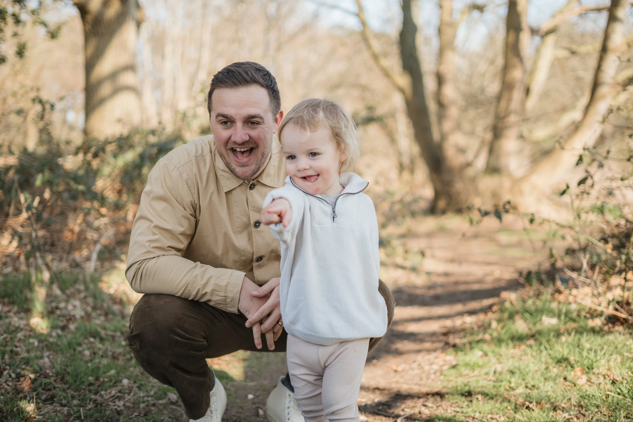 Relaxed family photography in a Suffolk woodland, capturing a playful moment between a parent and child, photographed by Gemma Wythe Photography.