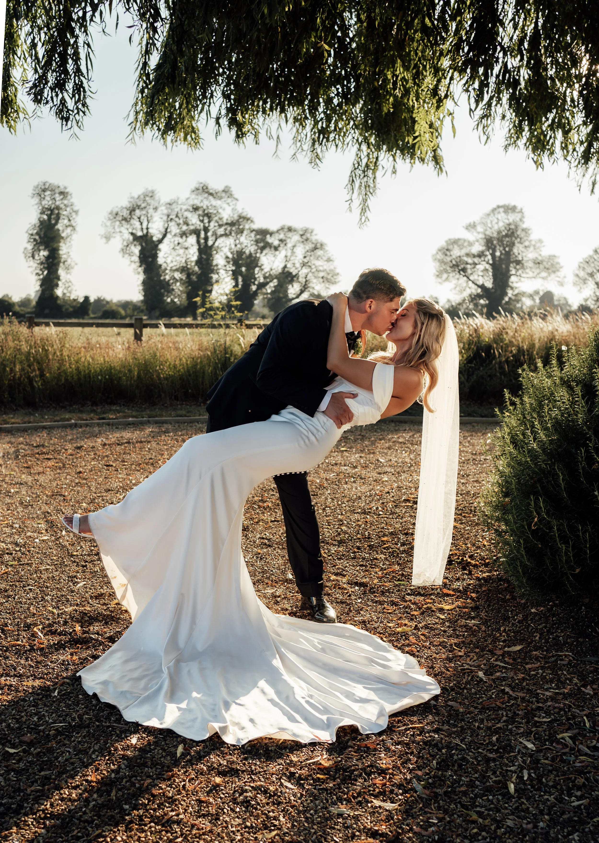 Bride and groom sharing a kiss during a romantic golden hour wedding portrait at Abbey Barns Norfolk
