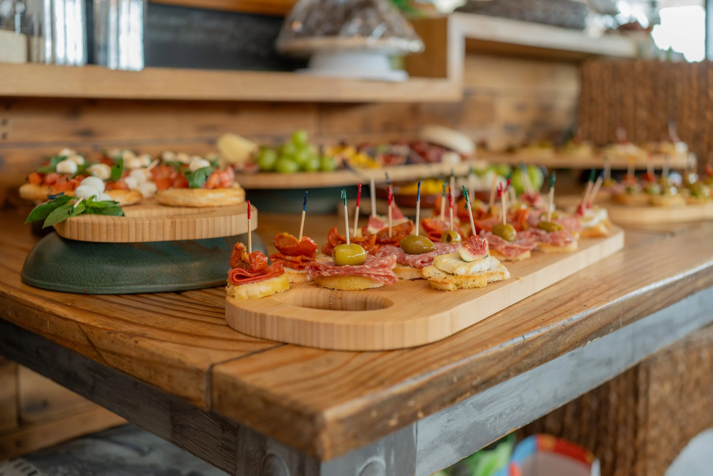 Assorted appetizers and finger foods on wooden serving boards at a buffet table.