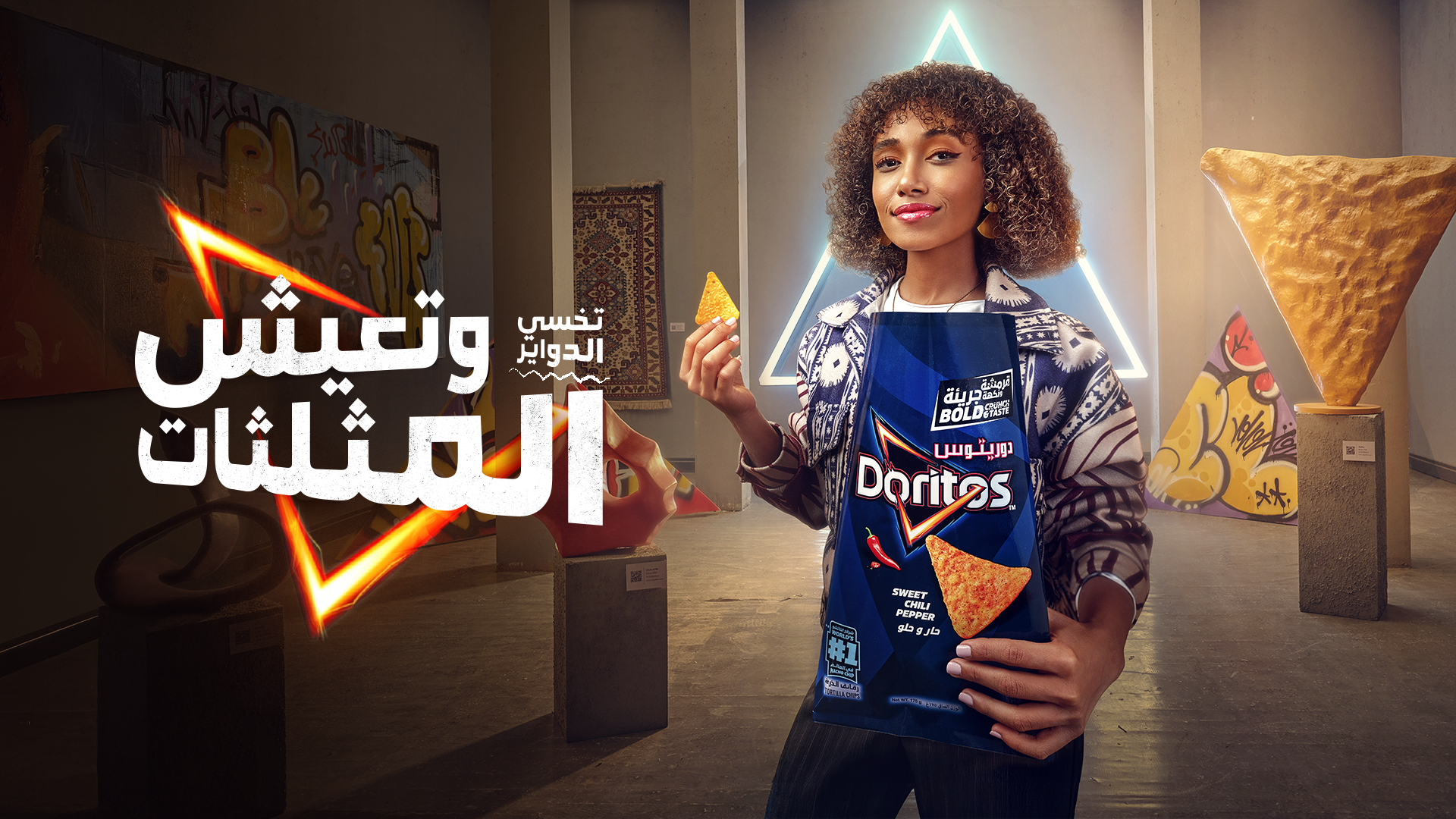 A woman holding a bag of Doritos chips in an art gallery with colorful graffiti and illuminated geometric shapes in the background, and Arabic text overlay.
