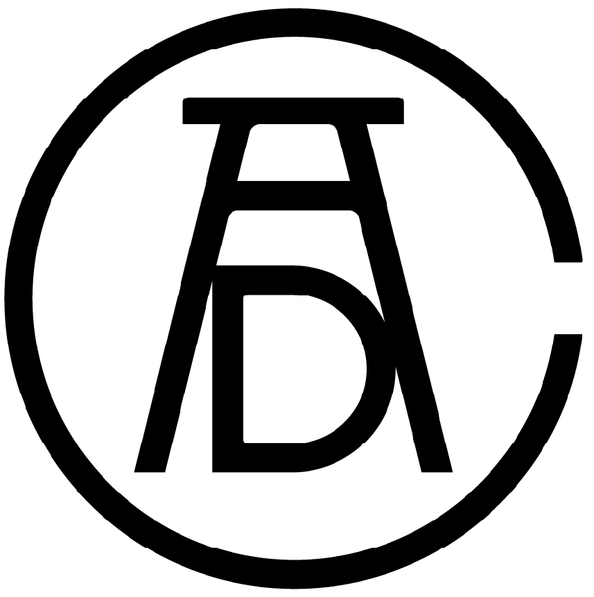 A black and white photograph of a person sitting on the ground and writing in a notebook, with a large tree nearby.