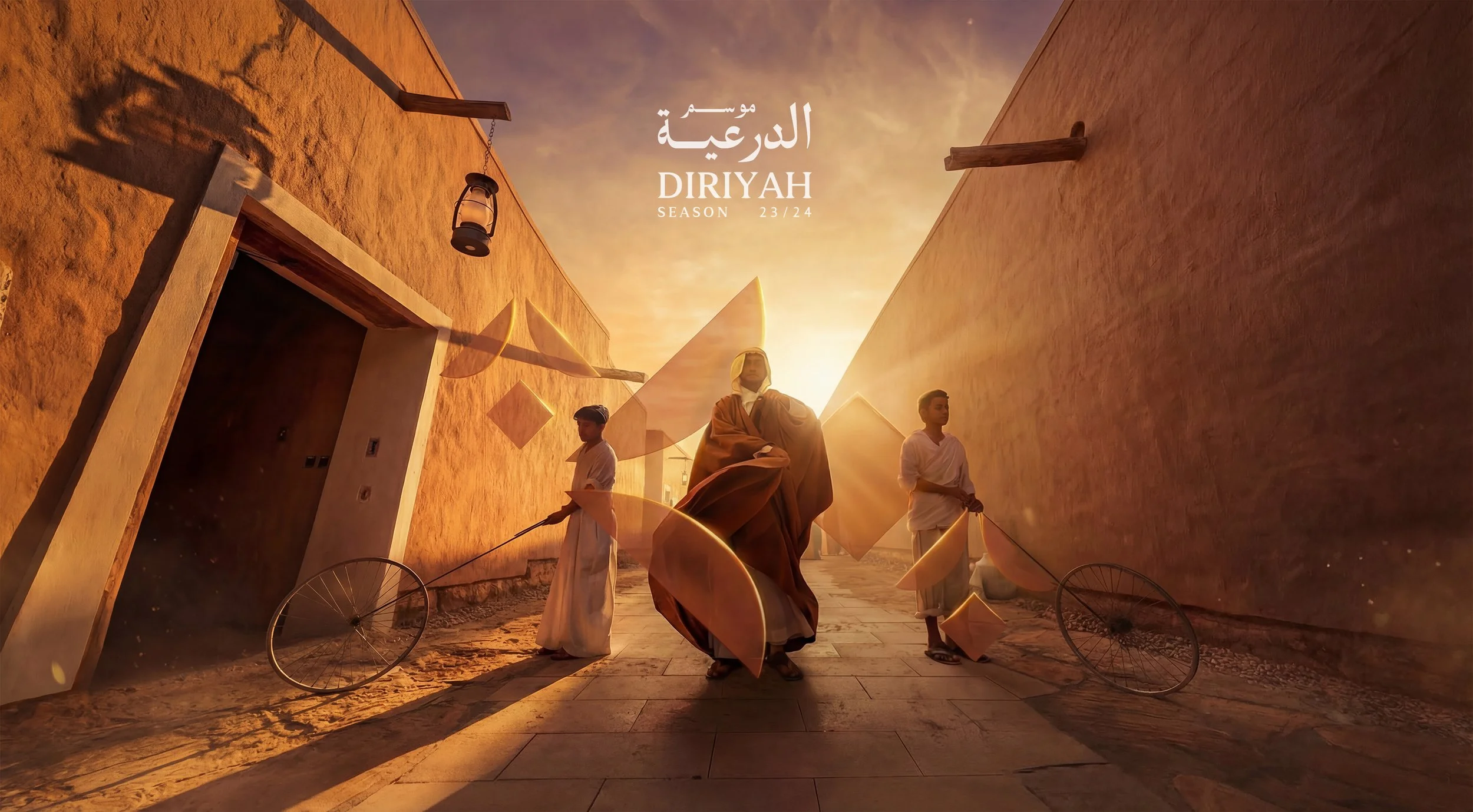 A sepia-toned scene in a narrow alley with three men, one in the center wearing traditional Middle Eastern clothing and two others on either side holding large circular frames on sticks. The background has a warm, glowing sunset sky and beige earthy buildings with hanging lanterns and geometric decorations, with text in Arabic and English indicating a series titled 'Diriyah' for the 23/24 season.