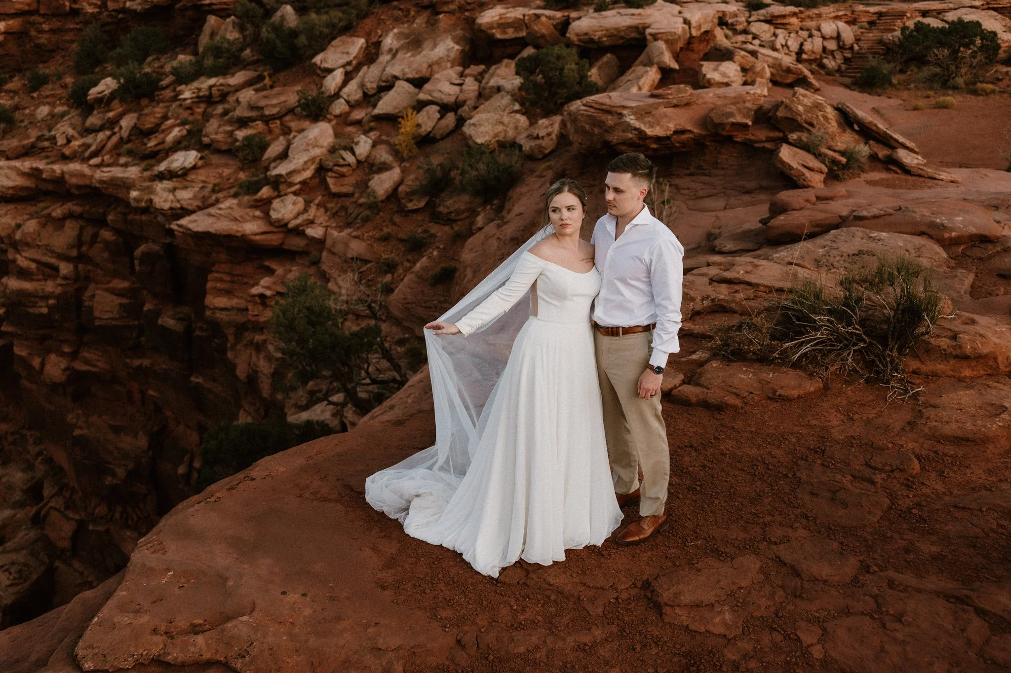 Wedding couple stands near the red rocky edge of Dead Horse State Park