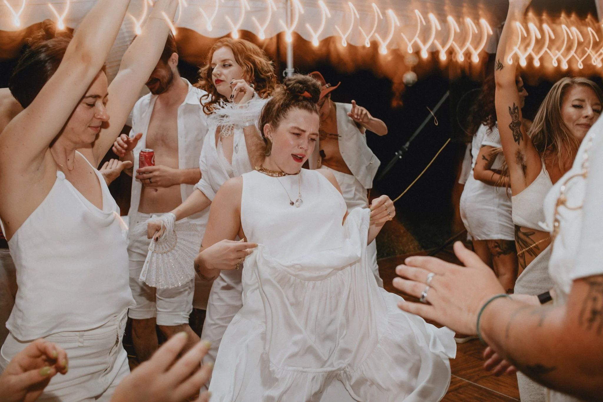 wedding guests in all white dance in a crowd