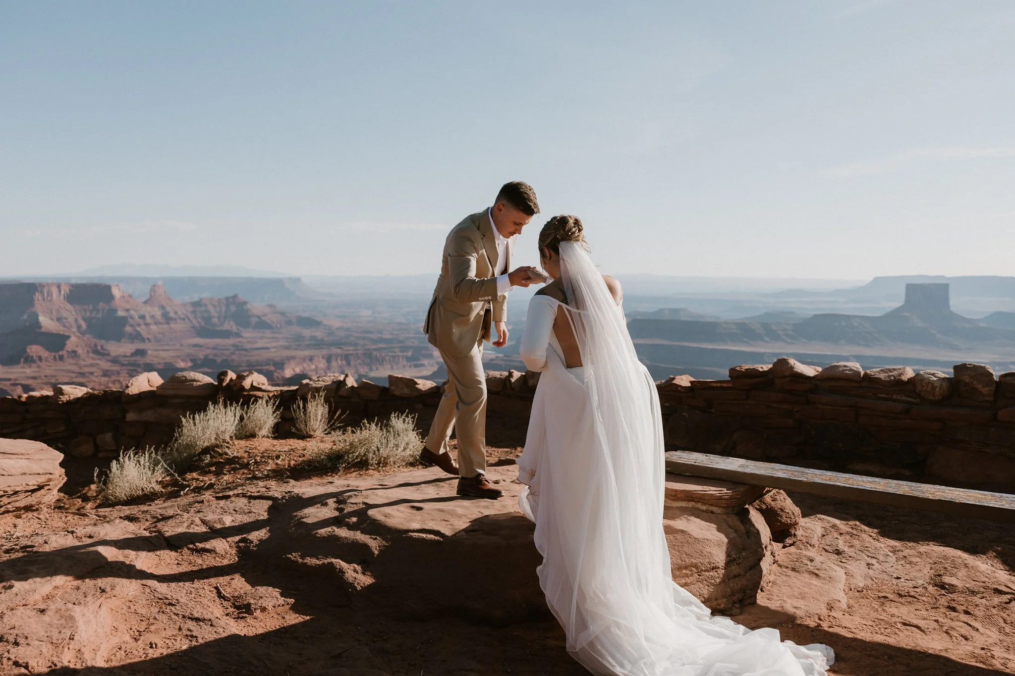 Groom helps Bridge onto the rocky ledge at the West Bench ceremony site in Dead Horse Point State Park, UT