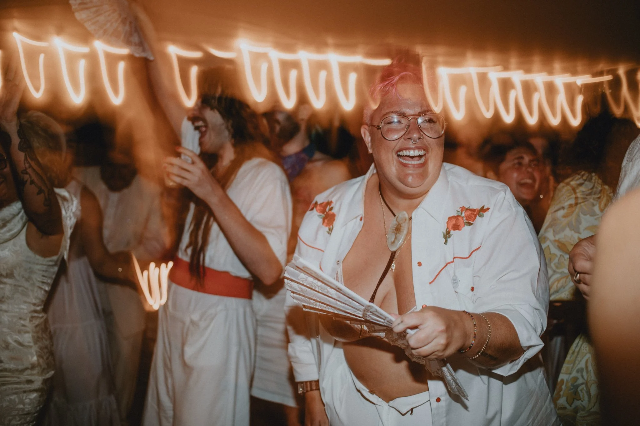 wedding guests, in all white, drink and dance together